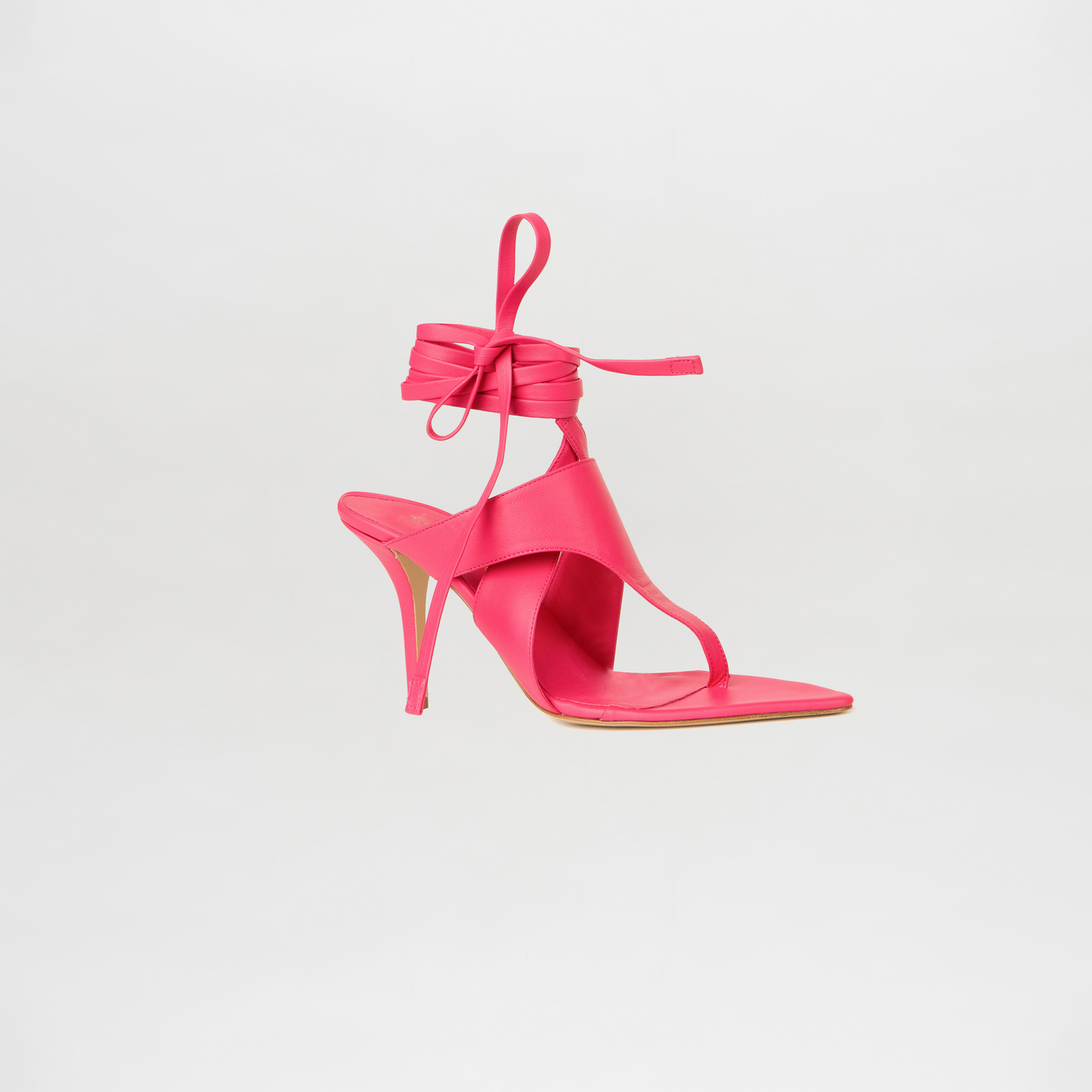Pink high-heeled sandal with ankle strap on a light gray background