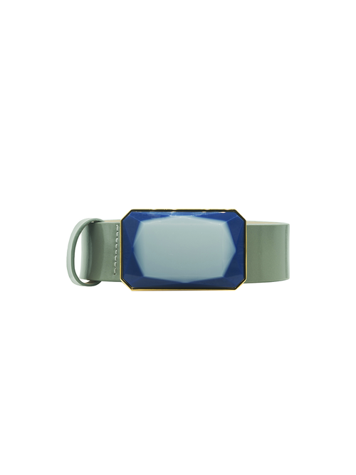 The Dora Belt Steel Blue is a green wristband featuring a blue, rectangular, faceted gem at the center. The blue gem is adorned with gold accents around the edges and can be shipped to your door in just a few days.