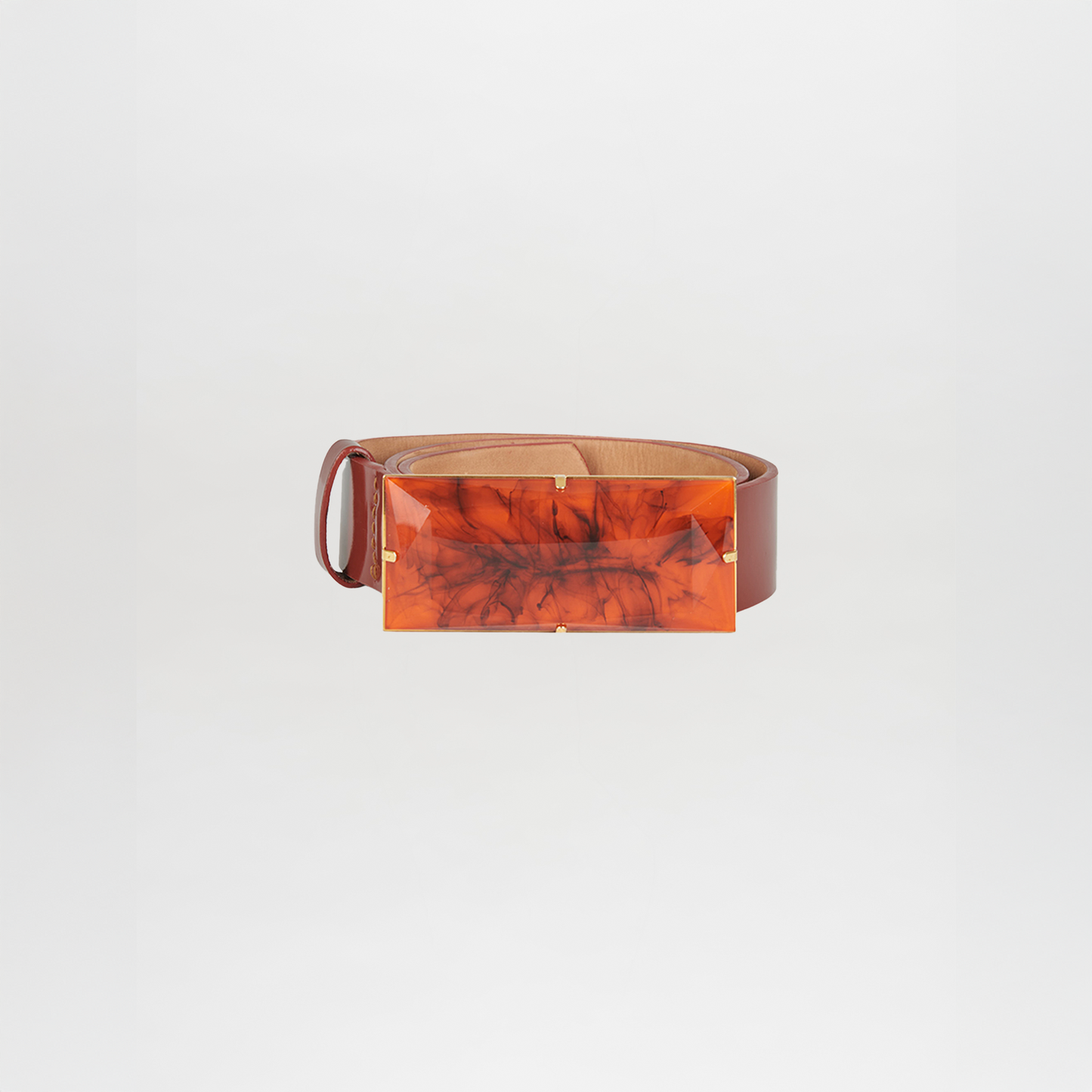 The Dora Belt Brick, inspired by Silvia Tcherassi’s signature style, features brick-colored leather and a large rectangular marbled orange buckle, shown against a plain white background.