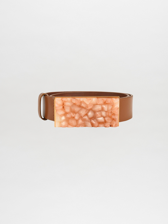 The Dora Belt Tan features a striking tan leather design with a large rectangular buckle that boasts a textured, amber-like finish, echoing the luxurious style reminiscent of Silvia Tcherassi.