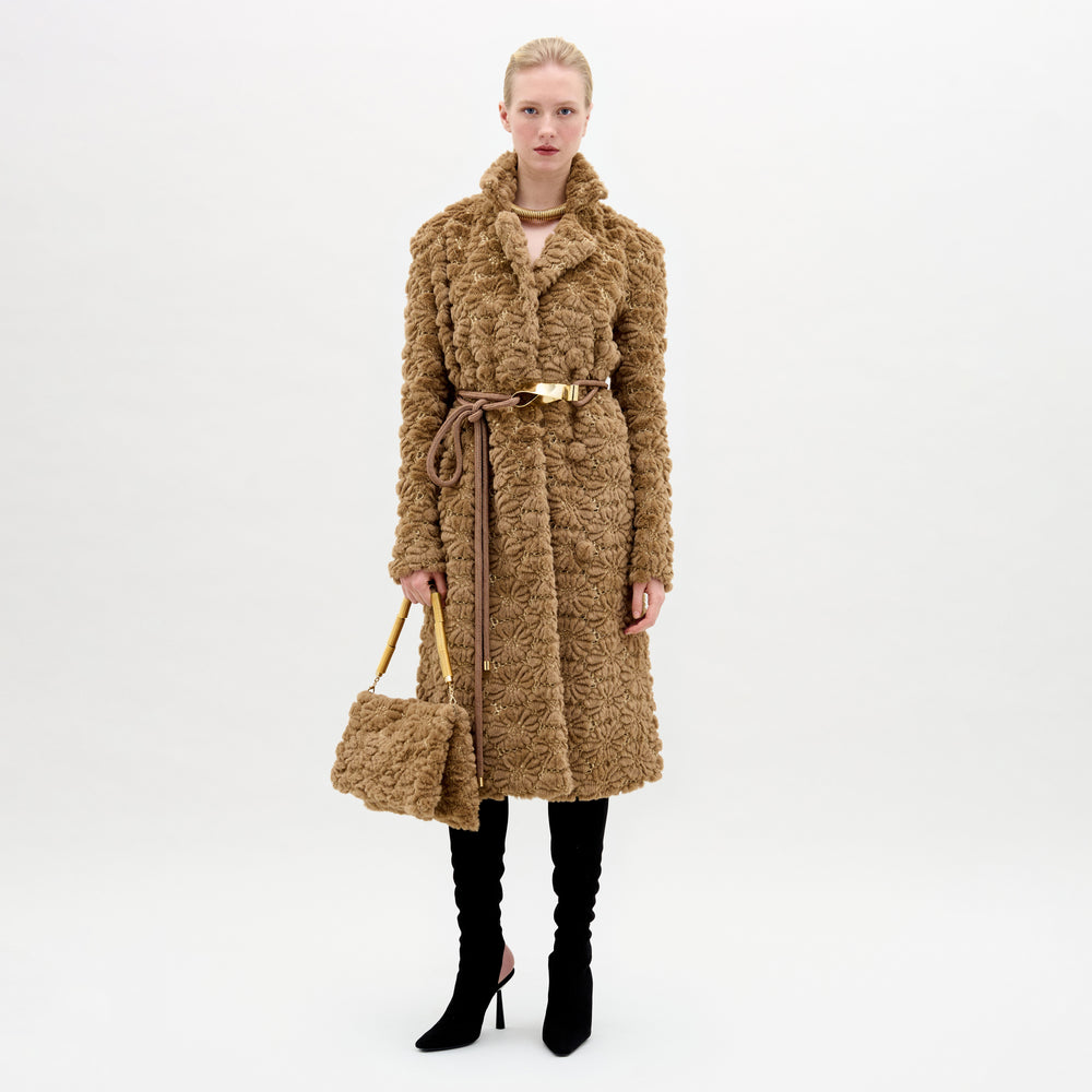 A woman wearing the Emerson Trench in color Camel with a Turni clutch in color Camel on a white background.