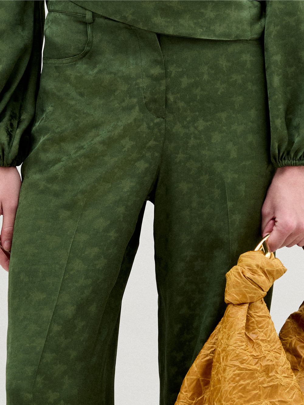 A person wearing the Emine Pant in color Hunter Green with a Sofia Bag Maxi in color Mustard on a white background.