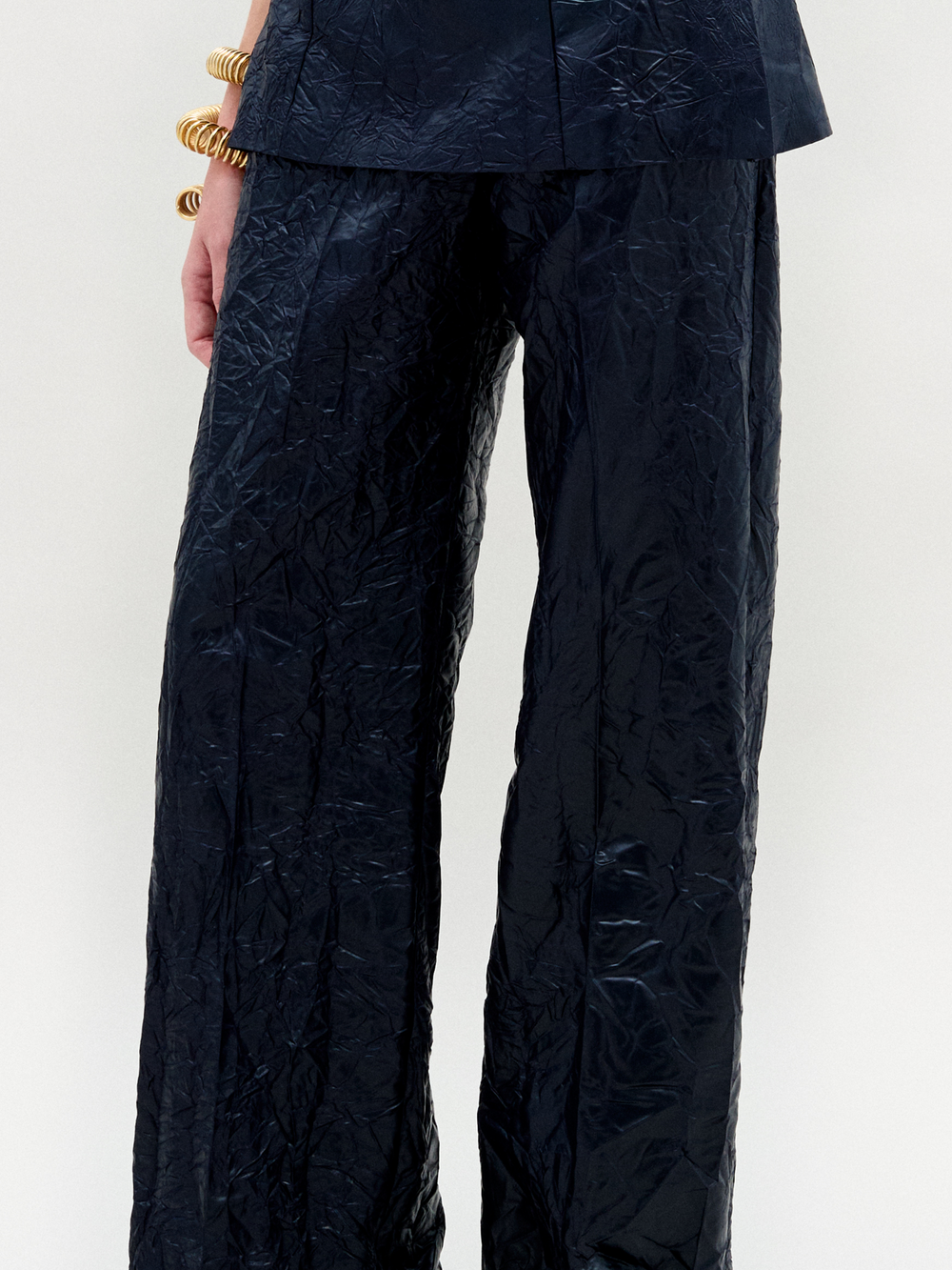 A person wearing the Emine Pant in color navy with a golden bracelet on a white background.