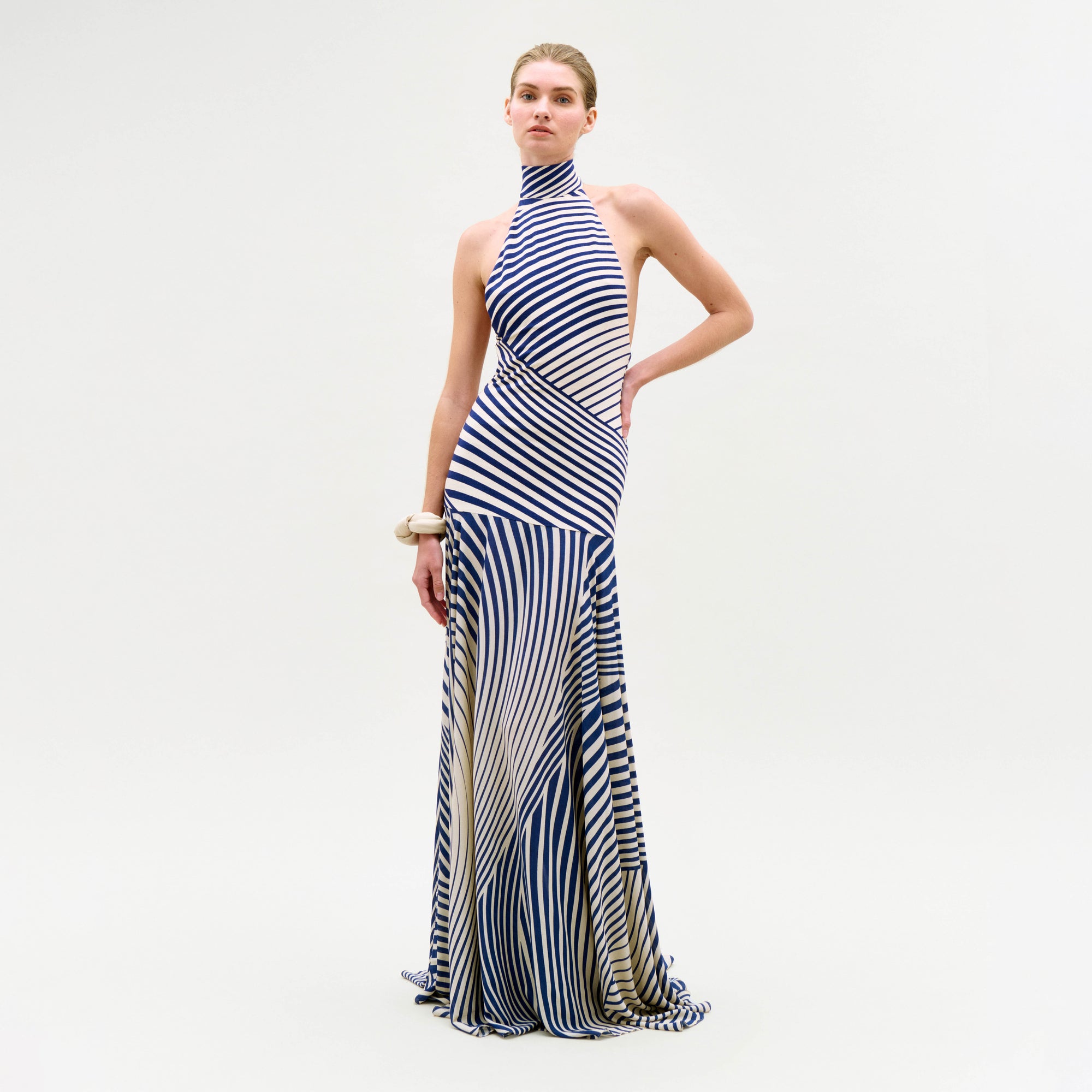 Woman wearing a long, striped dress on a plain background