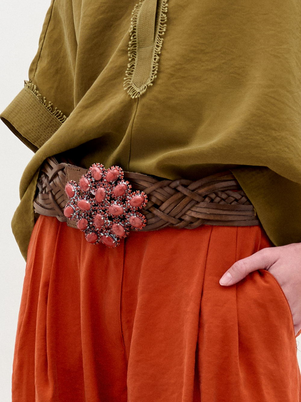 The Eines Belt is a wide, braided leather belt made in Italy with a bold buckle embellished with clustered red stones in a floral motif.