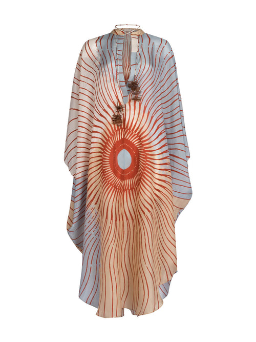 A Elea Tunic Sausalito Sunset with an orange and cream sunburst design, adorned with tassels and a circular centerpiece.