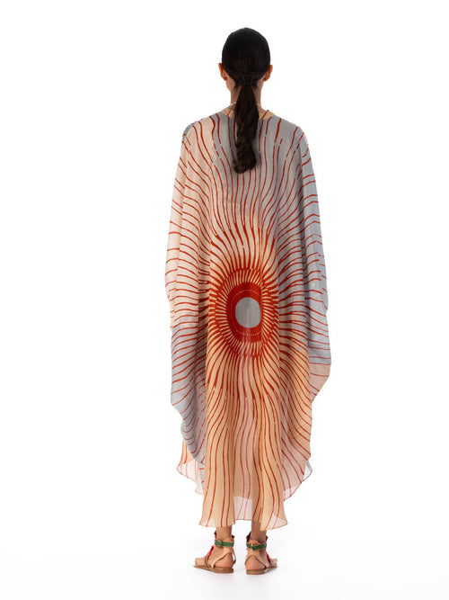 A Elea Tunic Sausalito Sunset with an orange and cream sunburst design, adorned with tassels and a circular centerpiece.