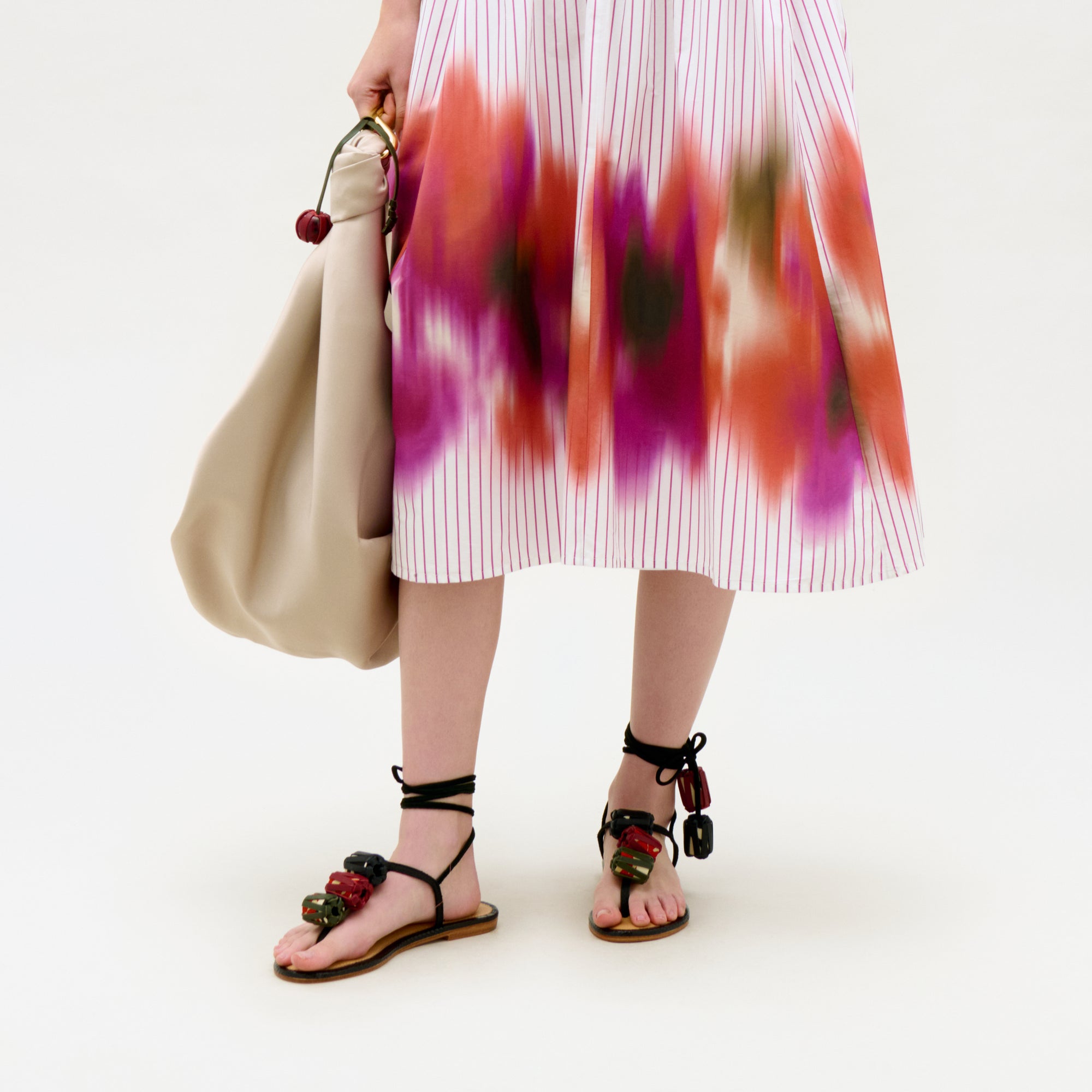 Person wearing a colorful dress with floral sandals on a white background