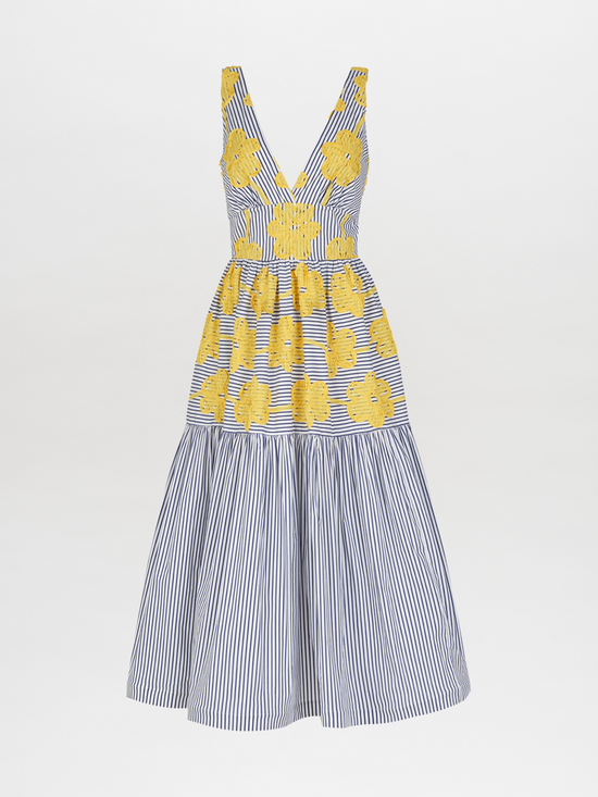 The Eugene Dress, adorned with yellow floral embroidery, showcases a sleeveless design with blue and white vertical stripes, a V-neckline, and a long-tiered skirt.