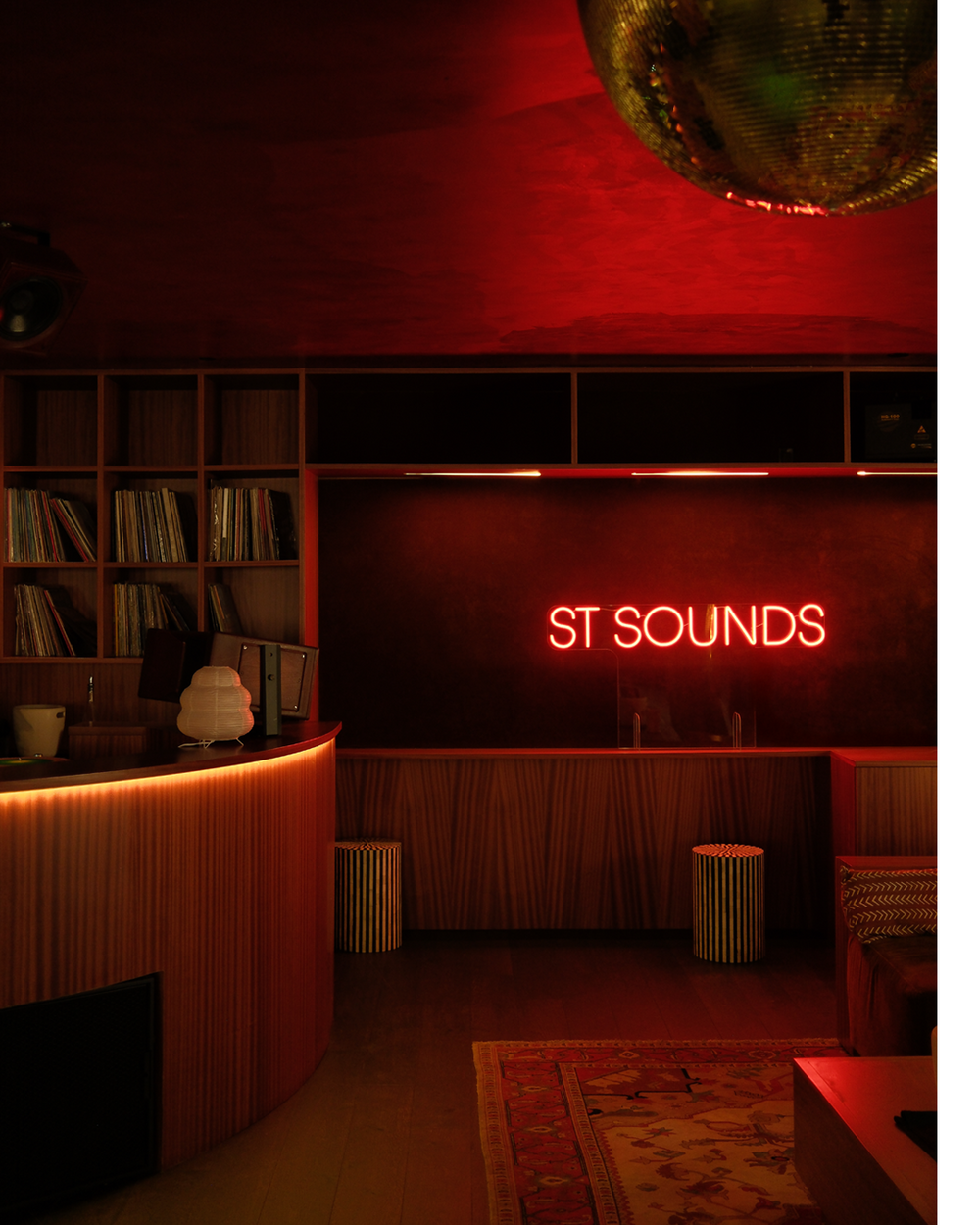 Neon sign reading 'ST SOUNDS' in a dimly lit room with bookshelves and decor.