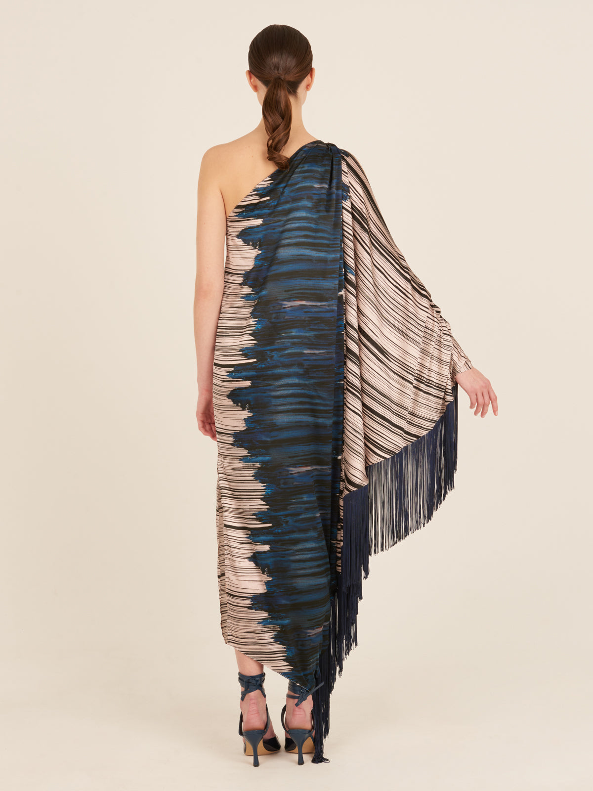 A blue and white fringed Alana Dress Indigo Linear, part of the Fall 2023 collection, is displayed on a mannequin with navy-blue fringes.