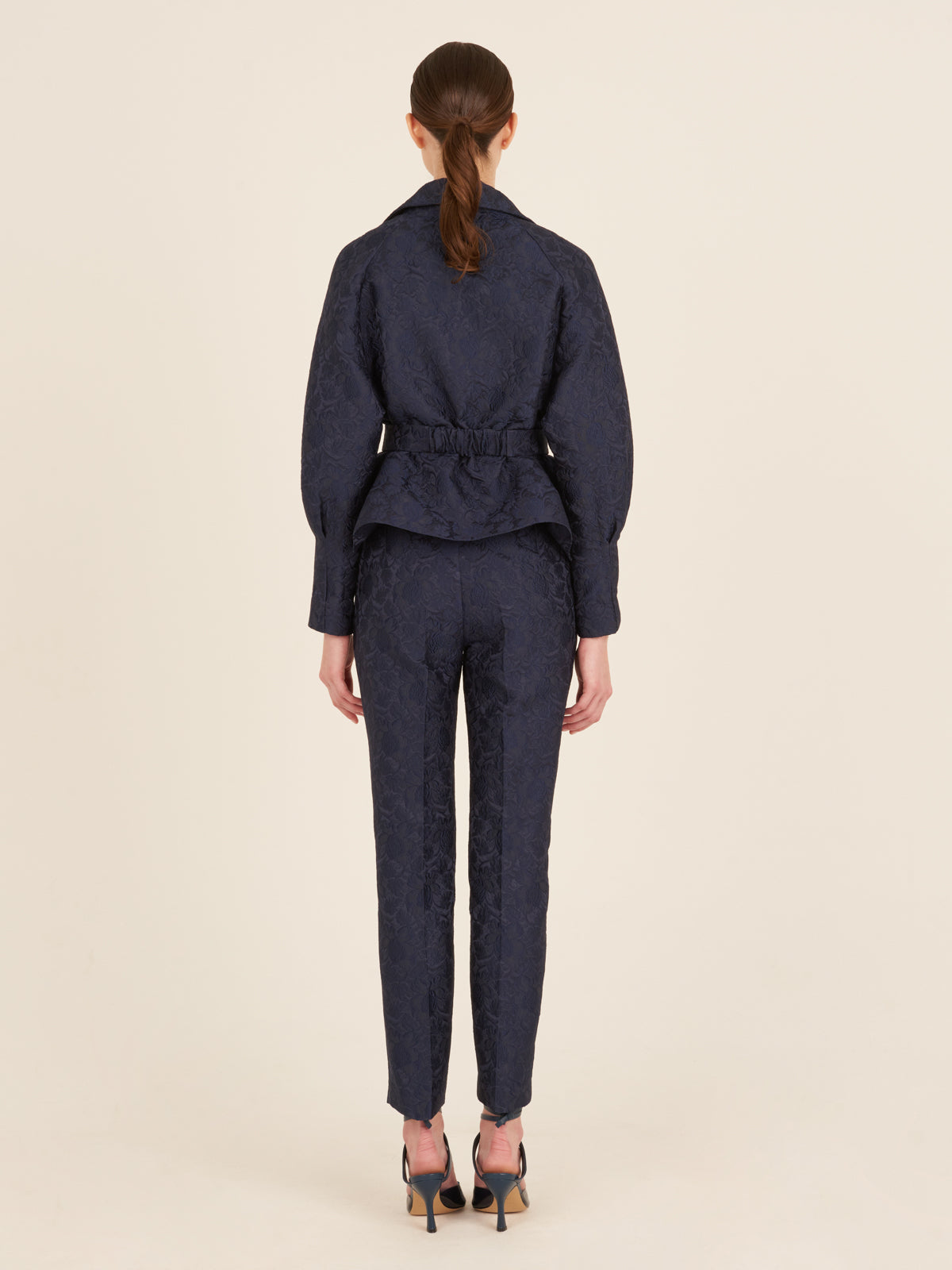 A woman's high-waisted Orion Pant Navy with a gold buckle.