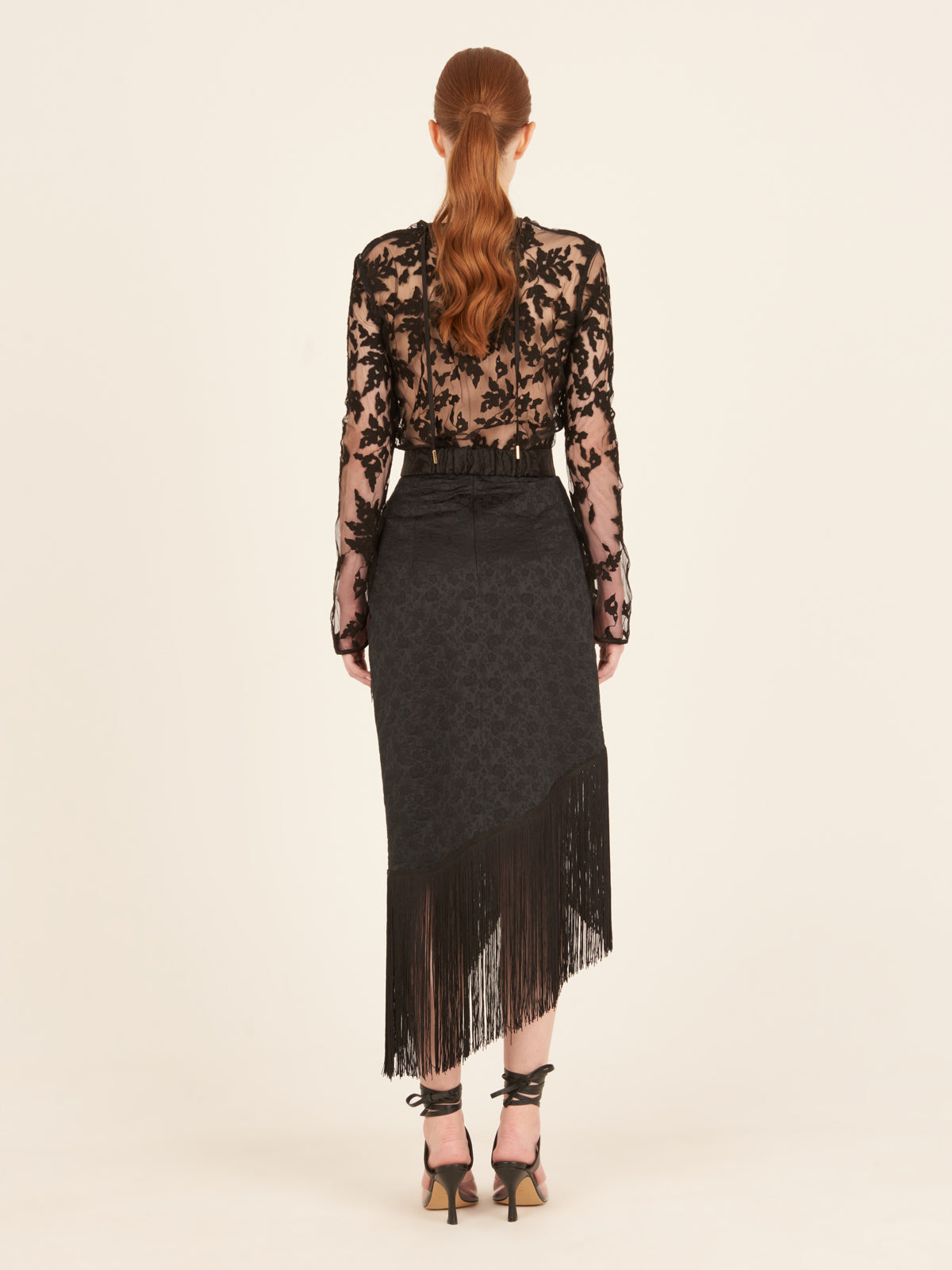 A black skirt with fringes on an asymmetrical hem, resembling the Natalia Skirt Black.