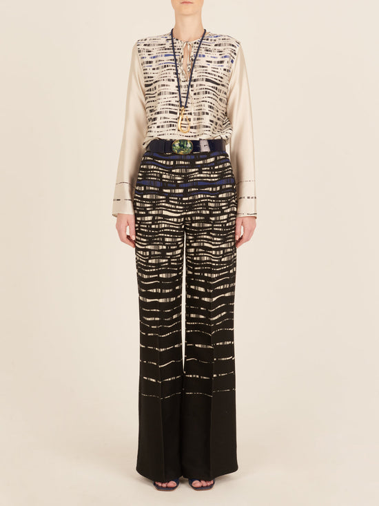 A person with long hair is wearing a Tosca Blouse White Black and matching pants in an abstract print, viewed from the back.