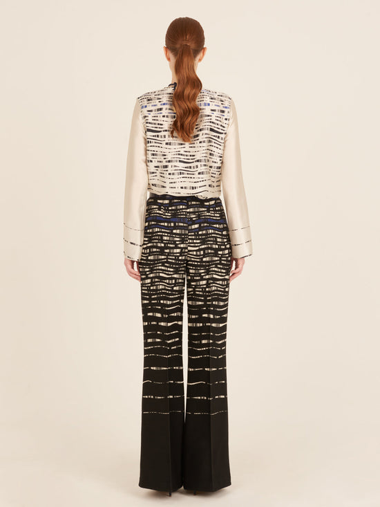 A person with long hair is wearing a Tosca Blouse White Black and matching pants in an abstract print, viewed from the back.