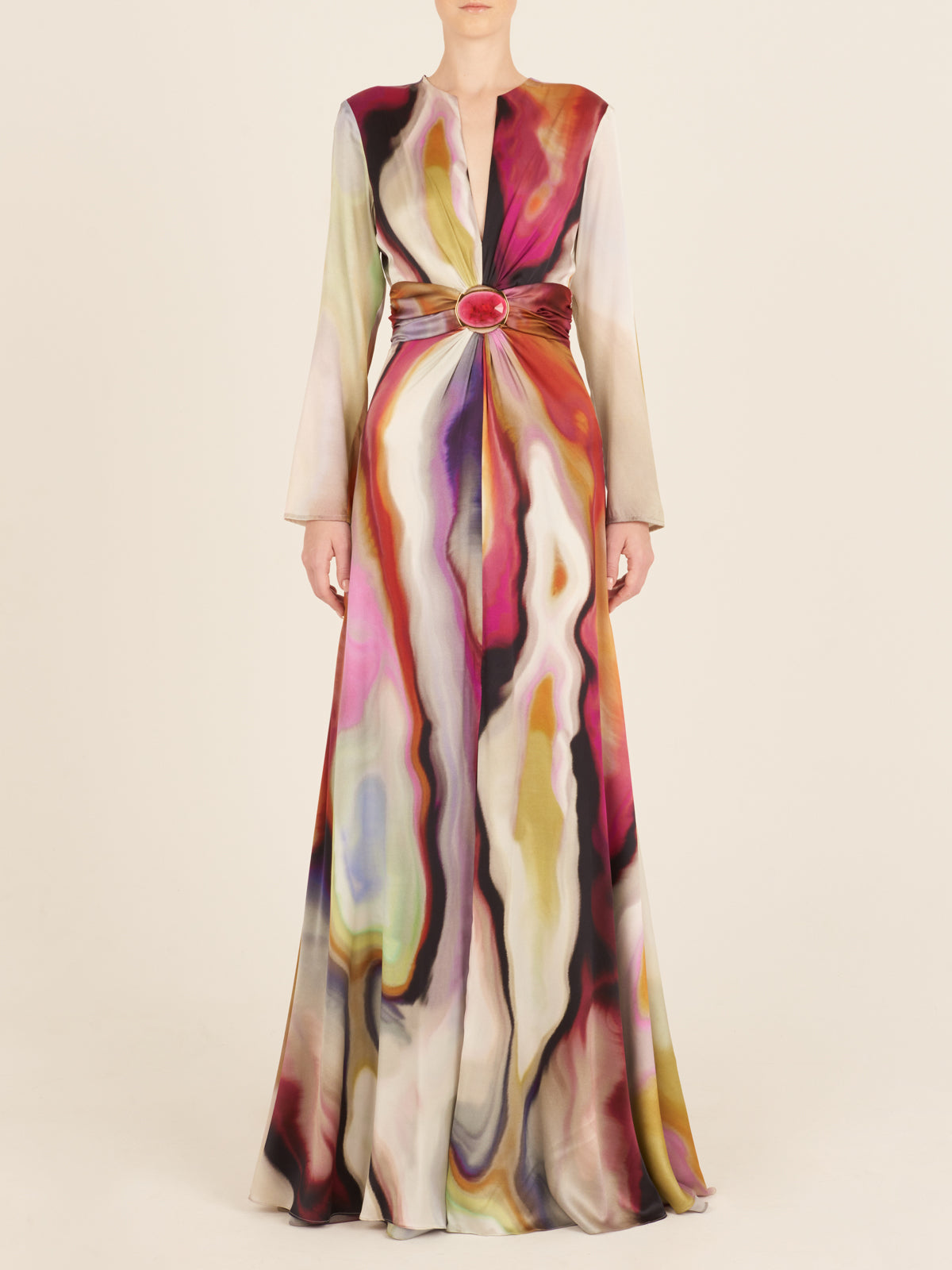 The Zarina Dress Iridescent Marble is a long-sleeve maxi dress made from luxurious Italian silk, showcasing a vibrant iridescent marble pattern with a cinched waist and a circular detail at the center.