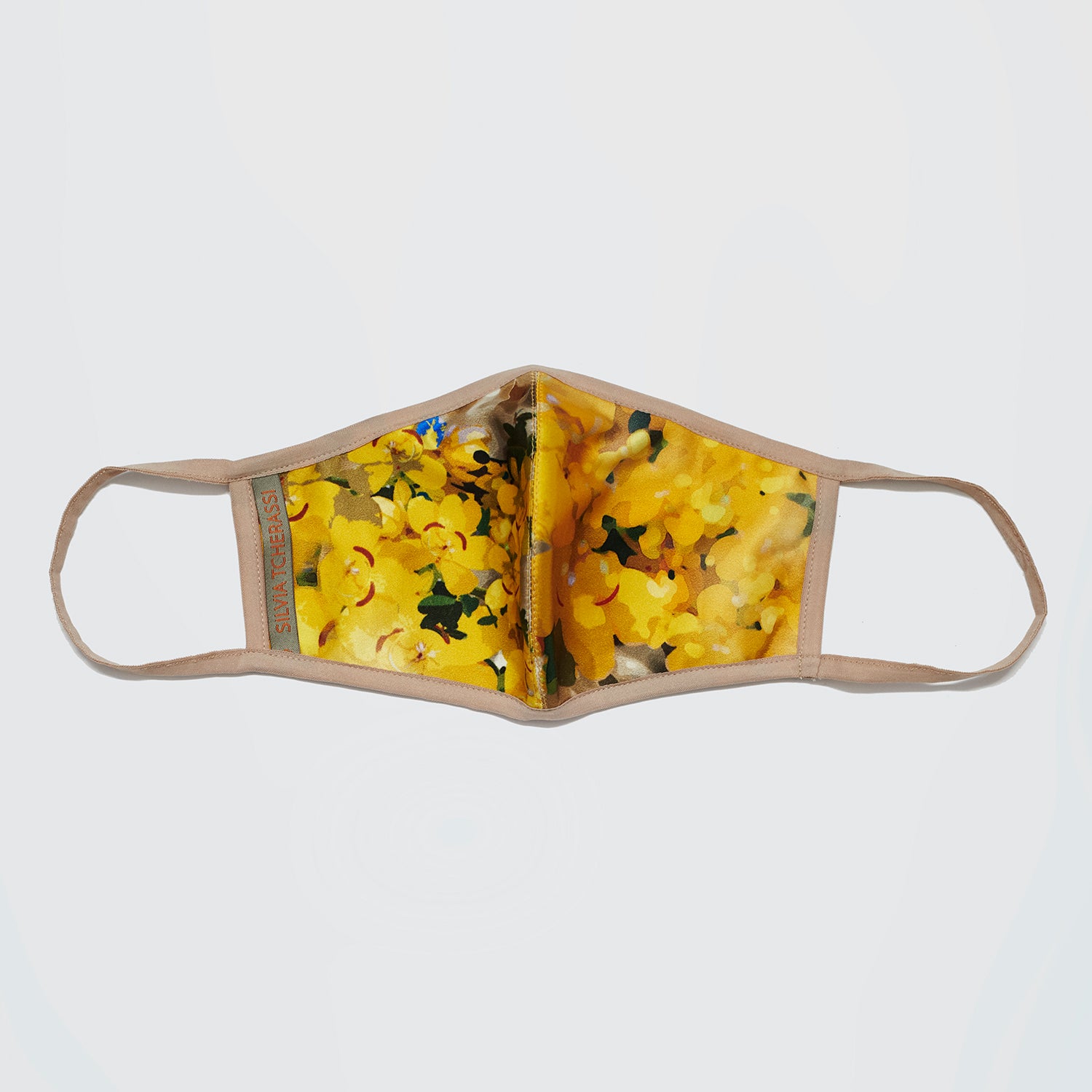 Face mask with yellow floral pattern and beige straps against a white background.