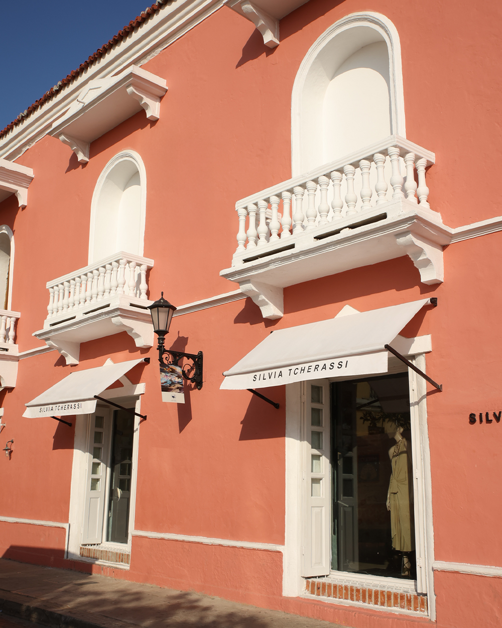 Pink building with white balconies and awnings featuring 'Silvia Tcherassi' brand.