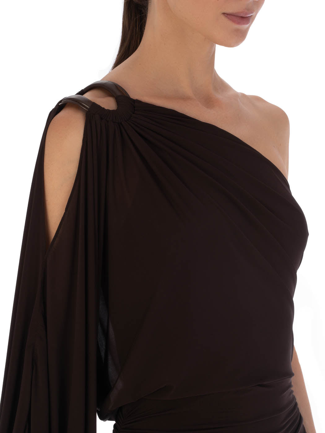 Woman in a Farah Dress Brown, a one-shoulder evening gown with leather ring detailing, posing in a studio setting.