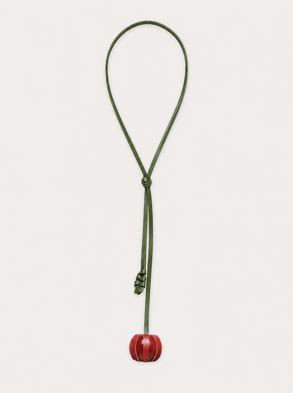 The Fruit Necklace features a green leather cord with a small red spherical pendant. A loose knot sits above the pendant, and the necklace is displayed on a white background.