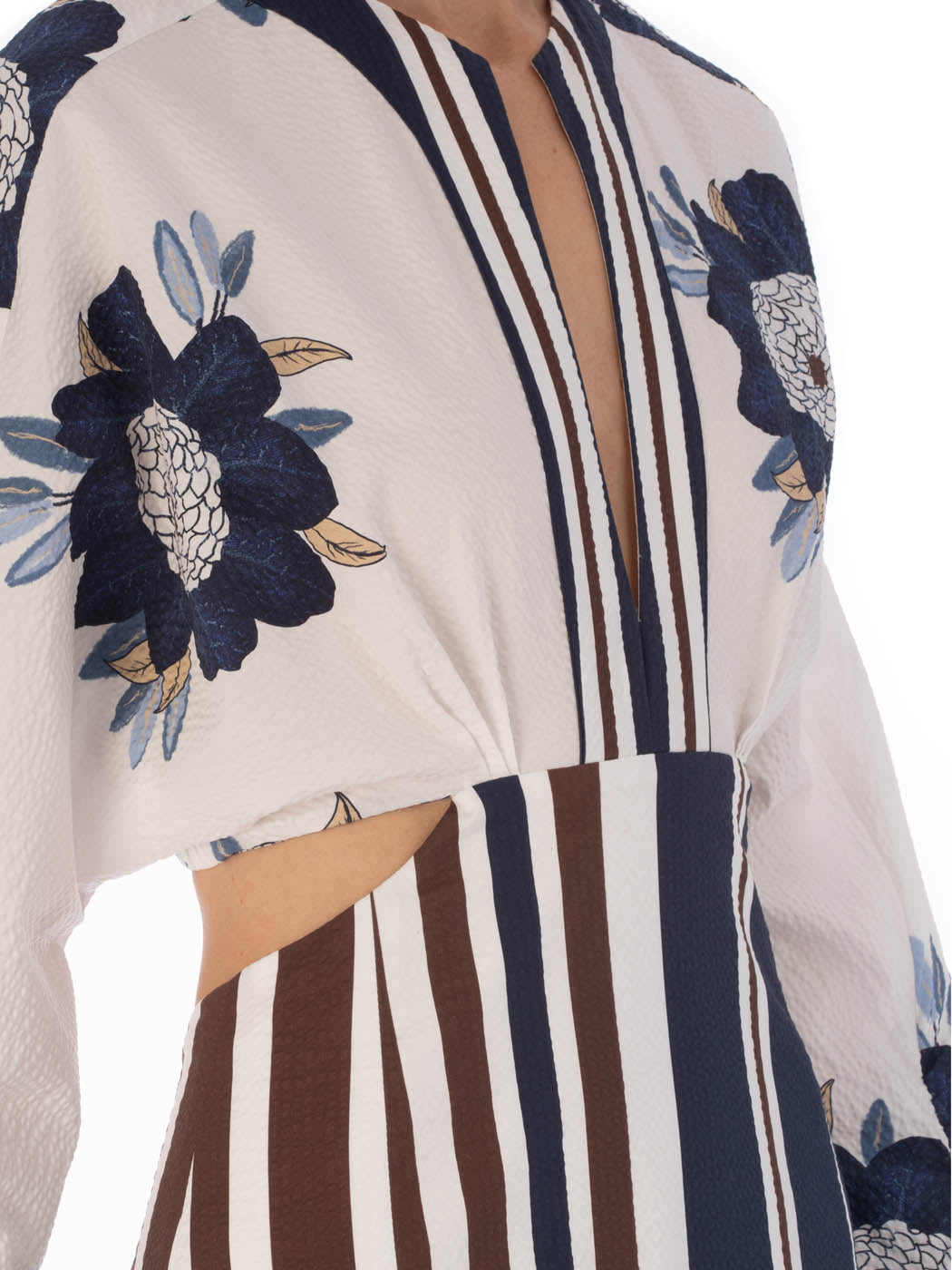 A long-sleeved Gabina Dress Multi Navy Brown Floral featuring a white base with blue floral patterns and horizontal navy stripes, designed with a flared skirt, isolated on a white background.