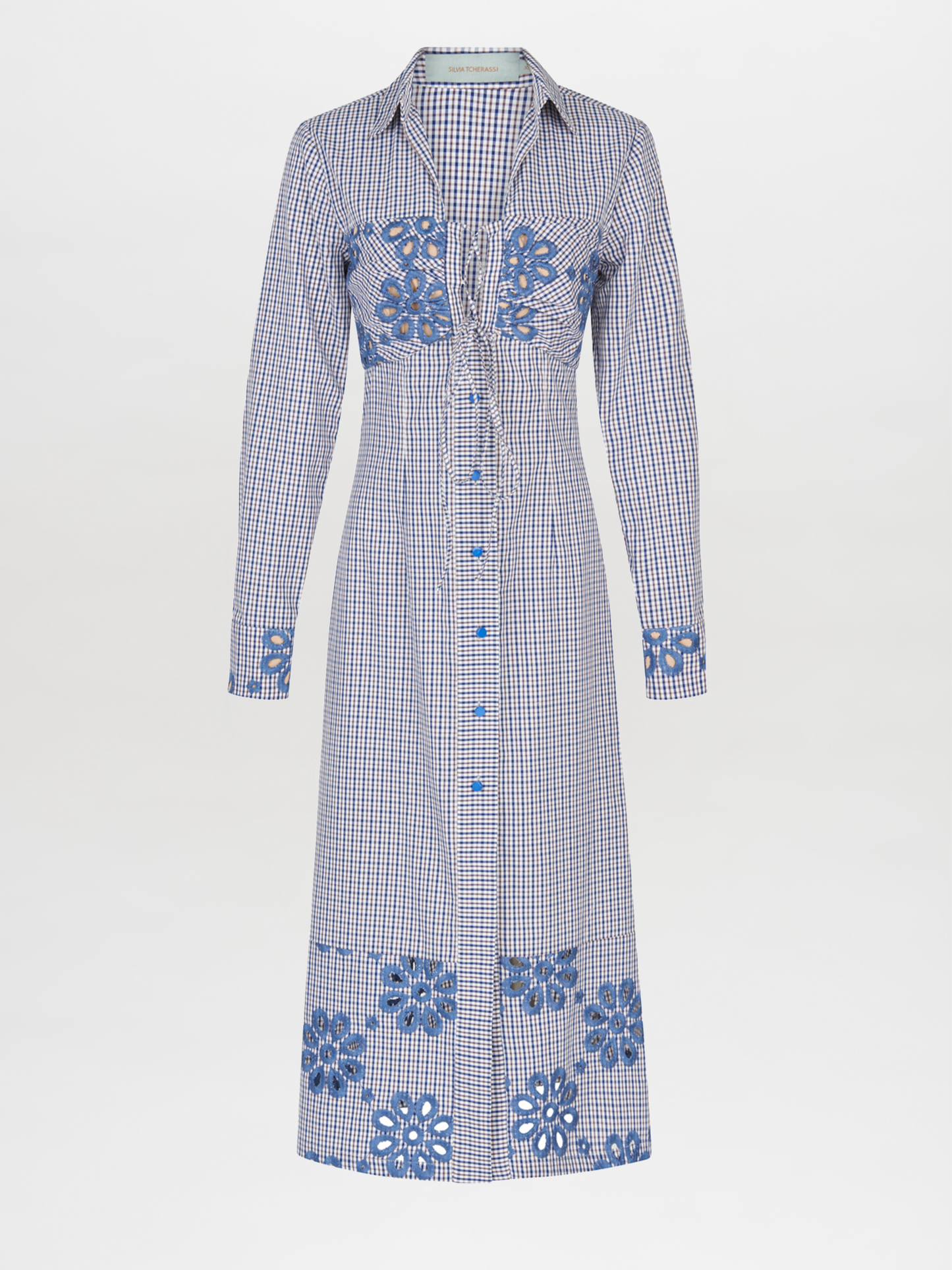 The Ganzoni Dress Navy Floral is a long-sleeve, button-down dress with a collar, featuring a blue and white checkered pattern and blue floral designs. This item is part of our Final Sale and is not eligible for return or exchange.