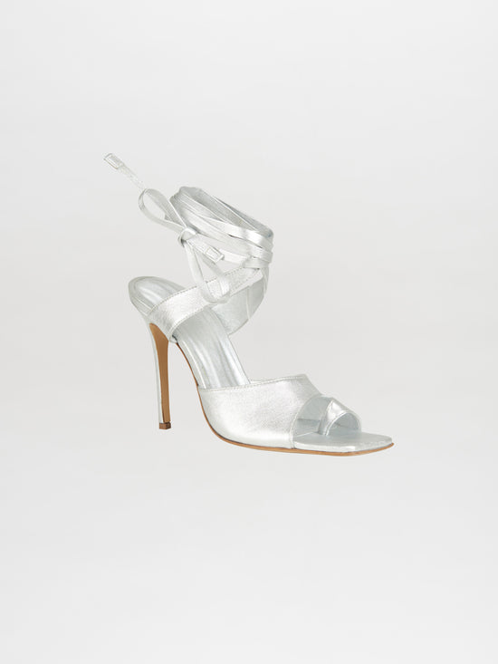 The Gia Borghini collaboration introduces the Golda Heels Silver, a stunning silver high-heeled sandal featuring ankle wrap straps on a light background, ideal for anyone who values style and elegance.