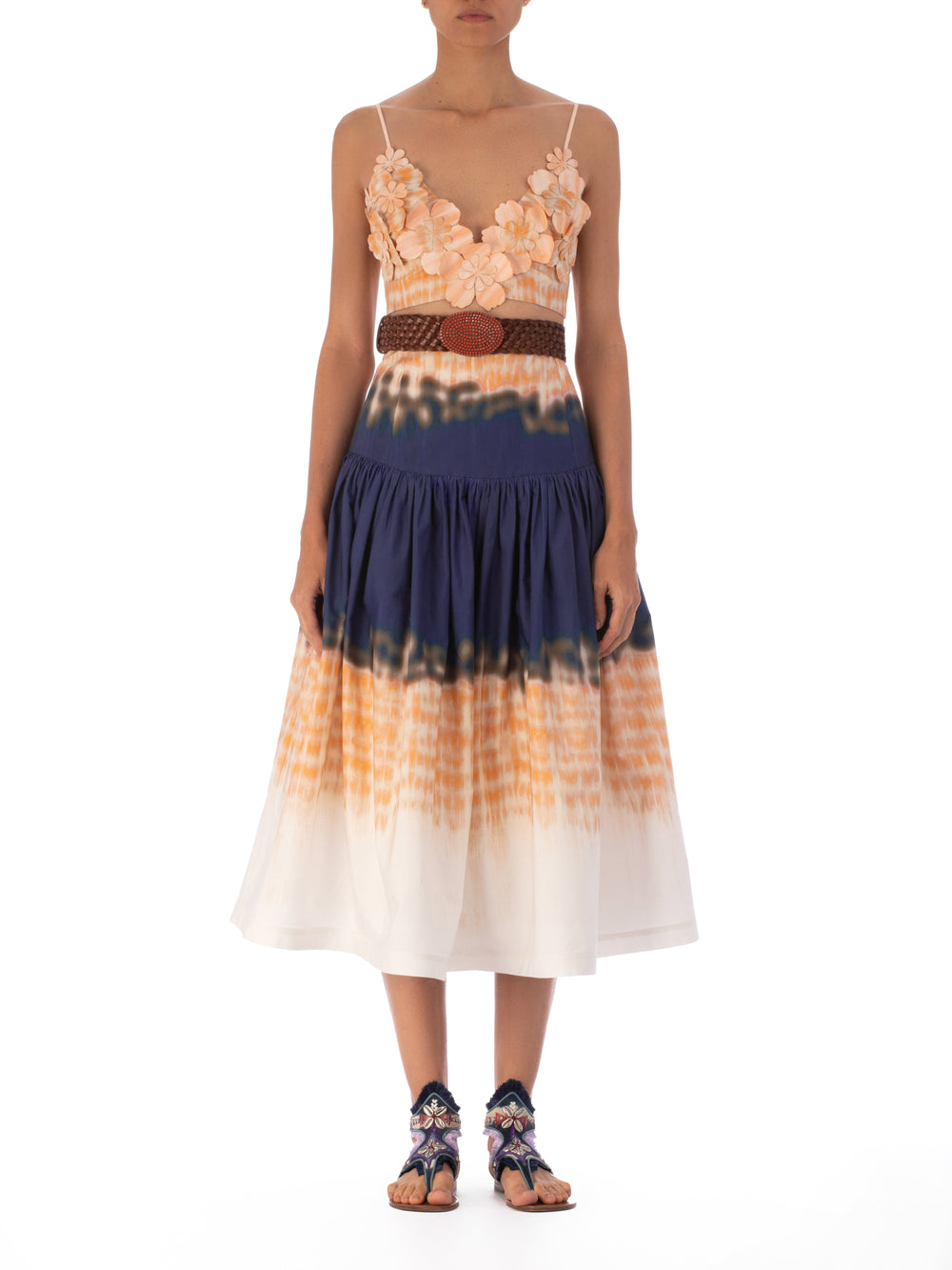 The Halsey Skirt Mediterranean Coral Blue is a high-waisted, flared midi skirt crafted from 100% cotton. It features an abstract multicolor print in navy, orange, and white with a vibrant tie-dye pattern that adds a playful touch to any ensemble.