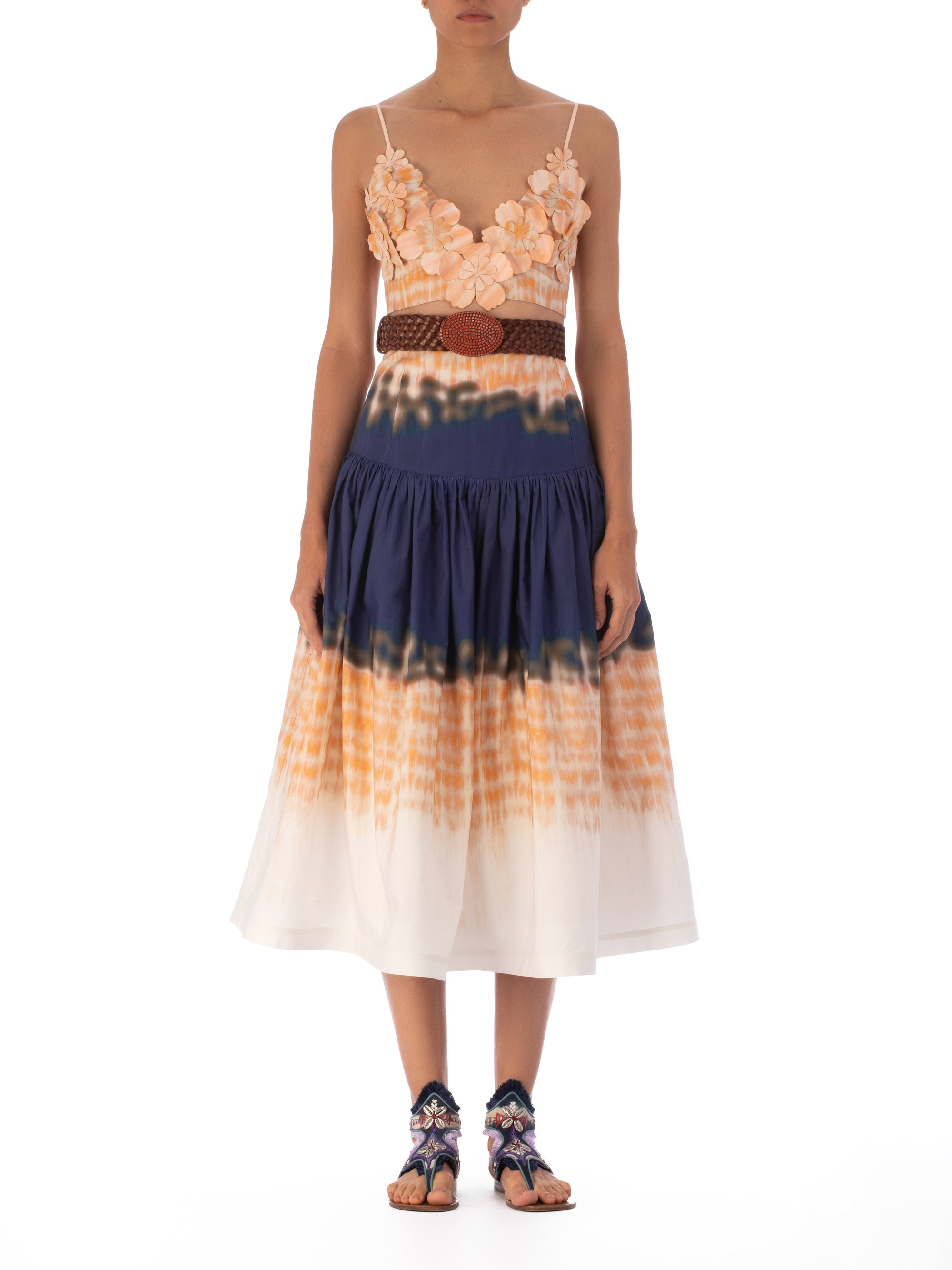 The Halsey Skirt Mediterranean Coral Blue is a high-waisted, flared midi skirt crafted from 100% cotton. It features an abstract multicolor print in navy, orange, and white with a vibrant tie-dye pattern that adds a playful touch to any ensemble.