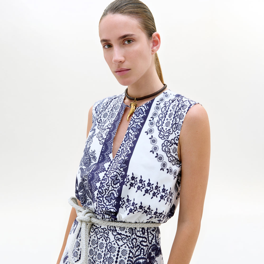 Woman wearing a sleeveless dress with blue floral pattern on a white background