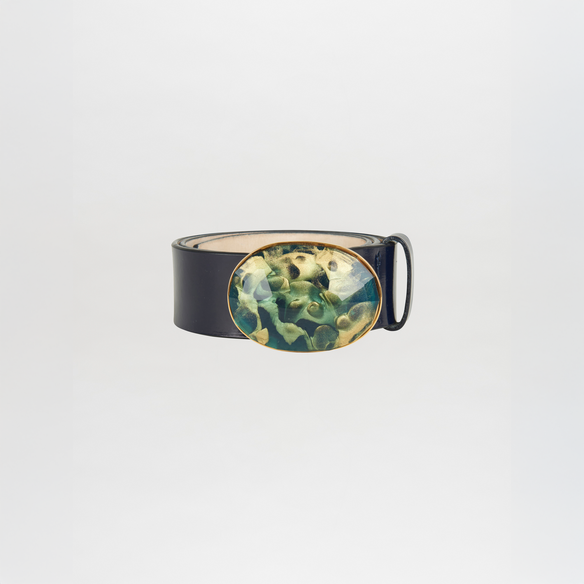 The Irene Belt Navy is a black Italian leather belt with a large oval buckle in green and gold abstract resin, shown on a plain white background. Ideal for elevating your Fall 2023 wardrobe.
