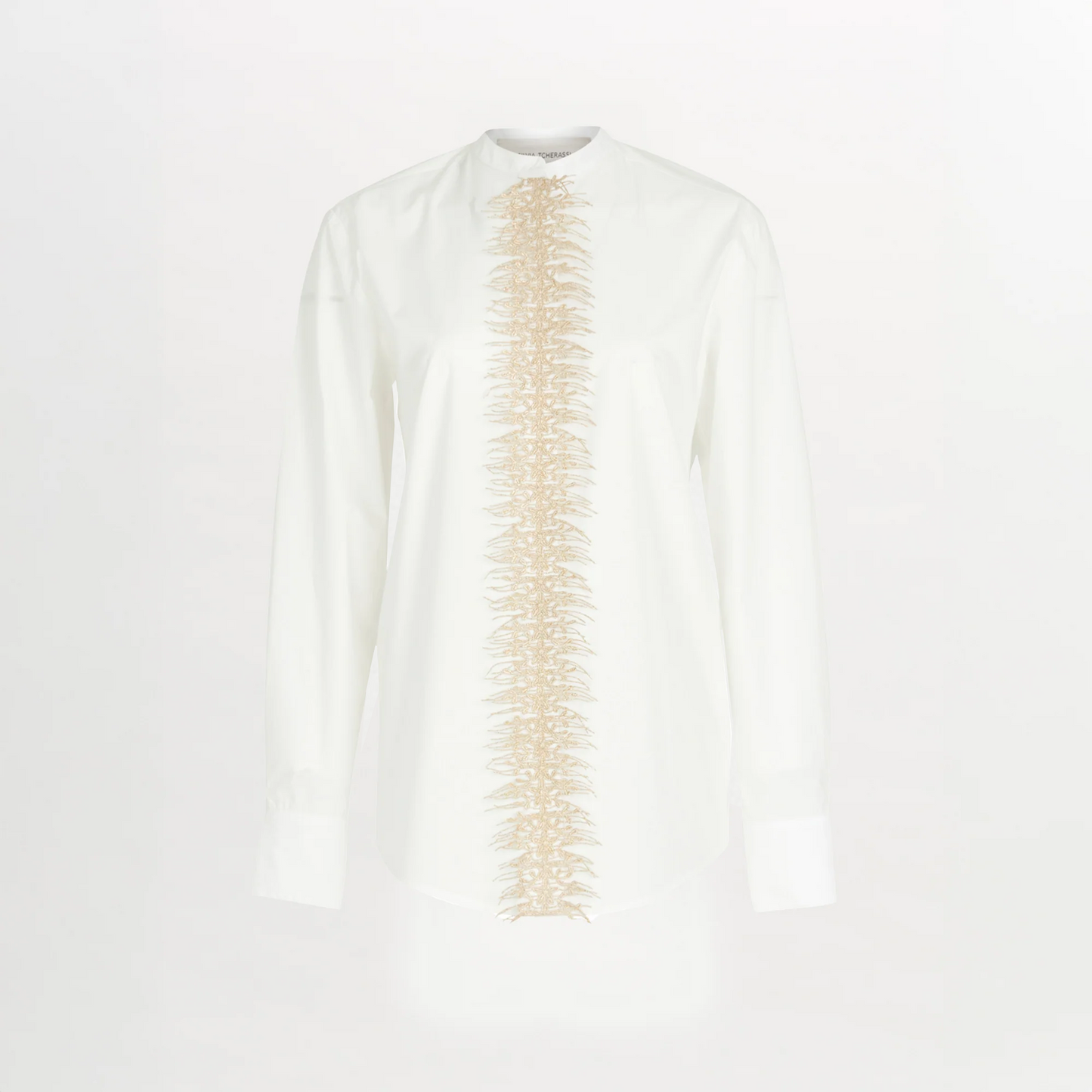 The Isabel Blouse White is a cotton poplin button-up with a beige embroidered vertical design down the center front.