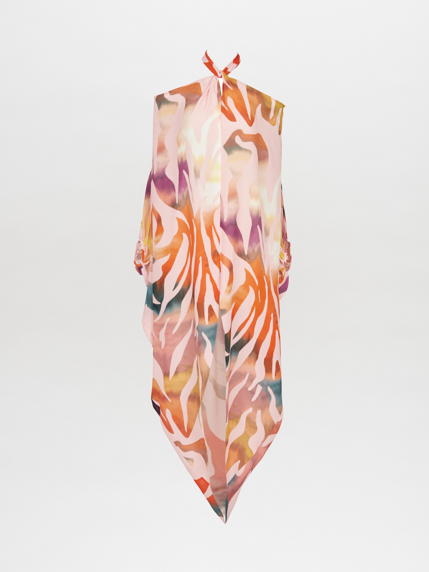 A colorful silk scarf with an abstract pattern drapes over a white background, echoing the vibrant hues of the Jacqueline Kaftan Blush Prismatic, featuring shades of orange, pink, and green.