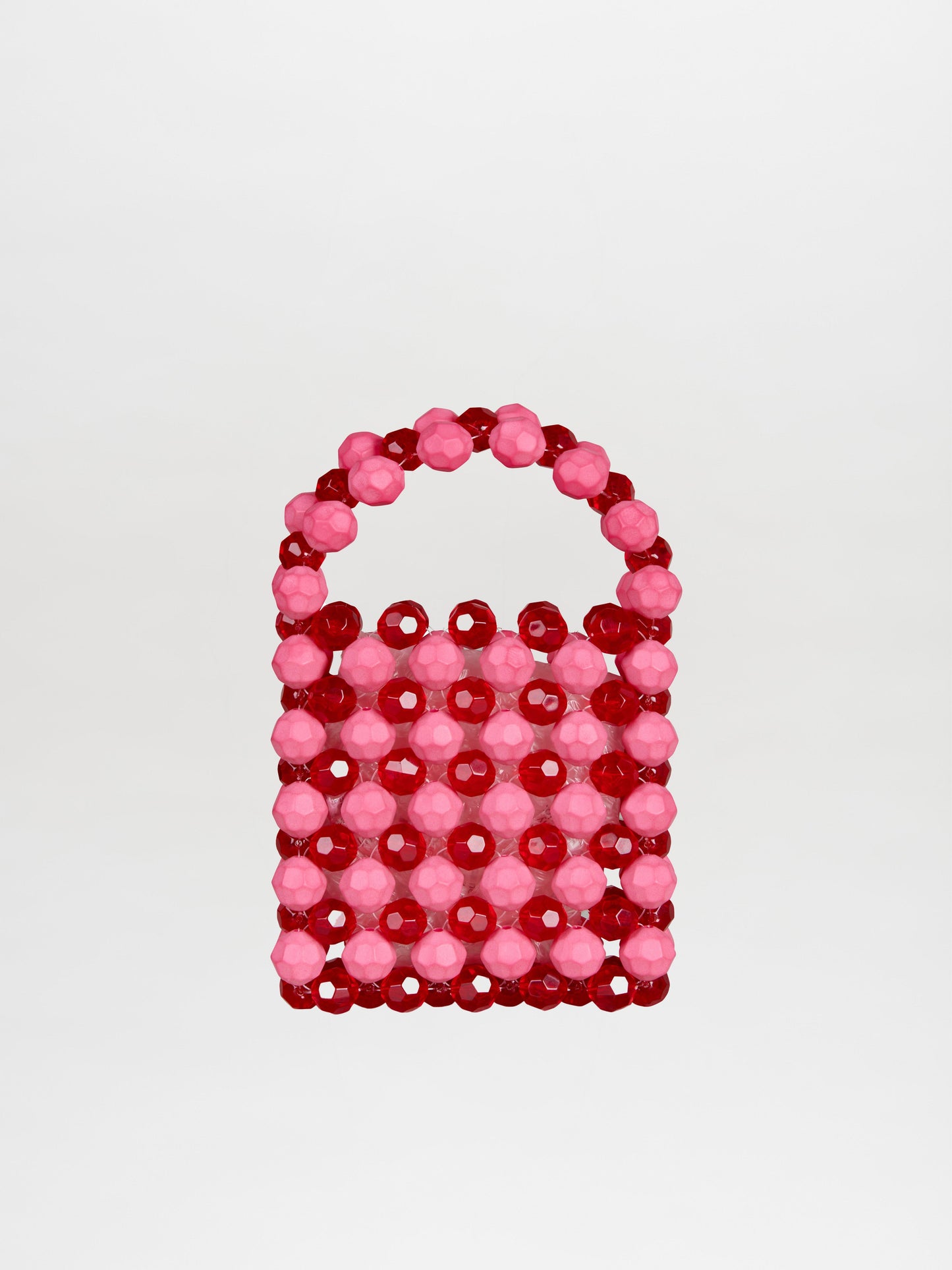 The Jasy Handbag Vermillon-Pink is a small, rectangular handbag adorned with red and pink beads, featuring a round bead handle that creates a textured effect against its plain background.