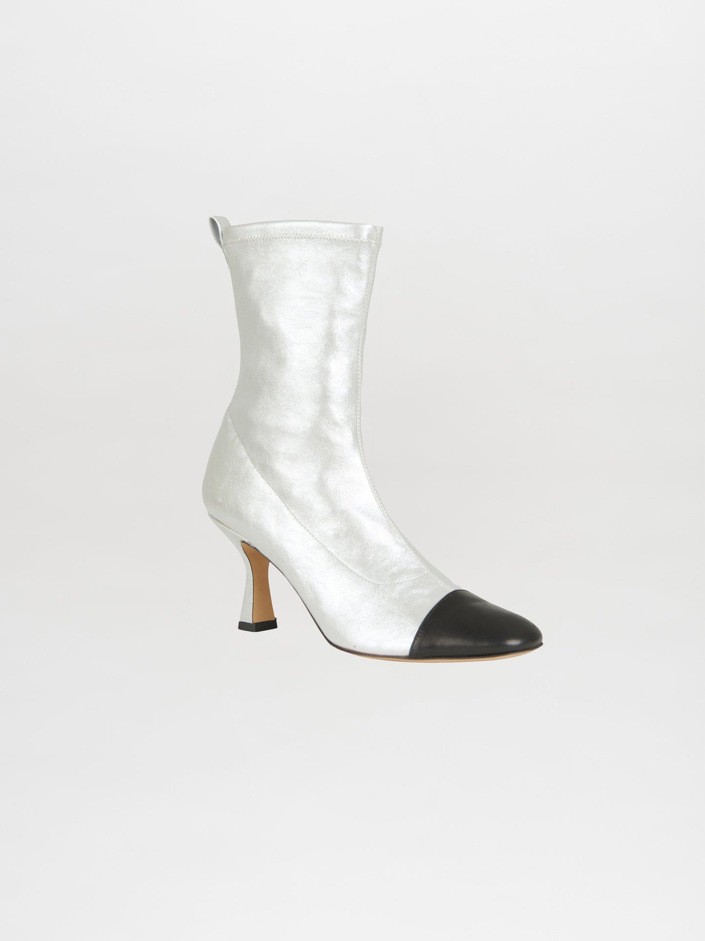 Introducing the Jelena Heel Boots Silver-Black, a captivating high-heeled creation by Italian artisans. Featuring a shiny silver body paired with a black cap toe, these two-toned boots are showcased against a sleek gray backdrop. Made from premium stretchy leather, they ensure an impeccable fit.