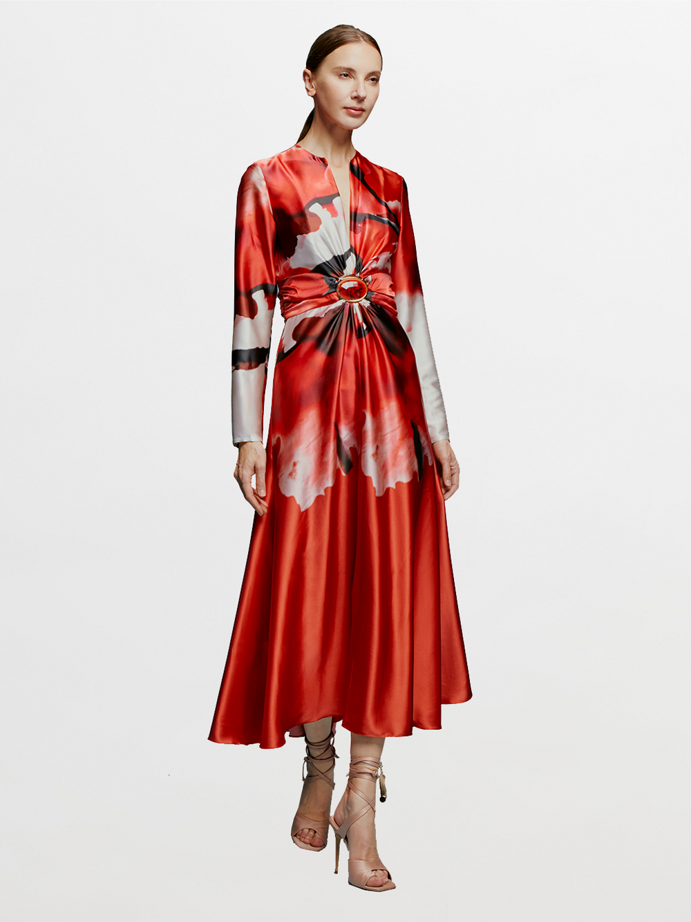 A woman wearing the Katarina Dress in Pomegranate Abstract Flowers, a long-sleeved dress with a gathered waist detail, stands against a light blue background paired with strappy nude heels. The date September 2nd appears softly highlighted in the background.