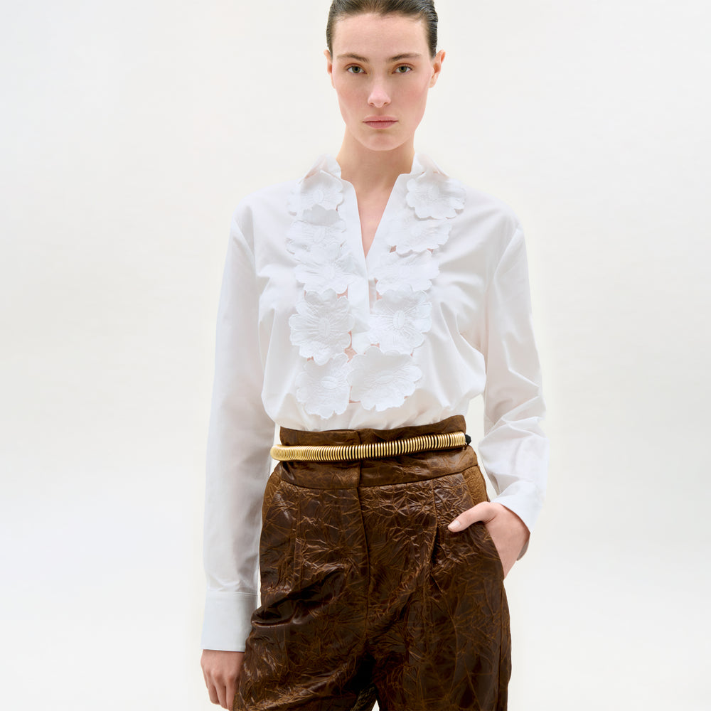 Woman wearing a white blouse and brown pants on a white background