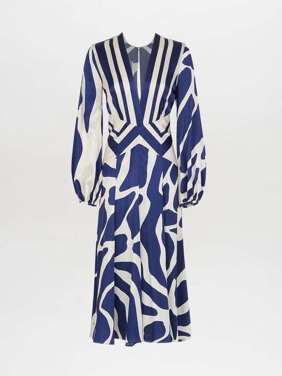 The Kathryn Dress Navy White Mosaic is a knee-length piece with a deep V-neckline and long sleeves, featuring a bold blue and white mosaic print that captures the essence of Spring 2023.