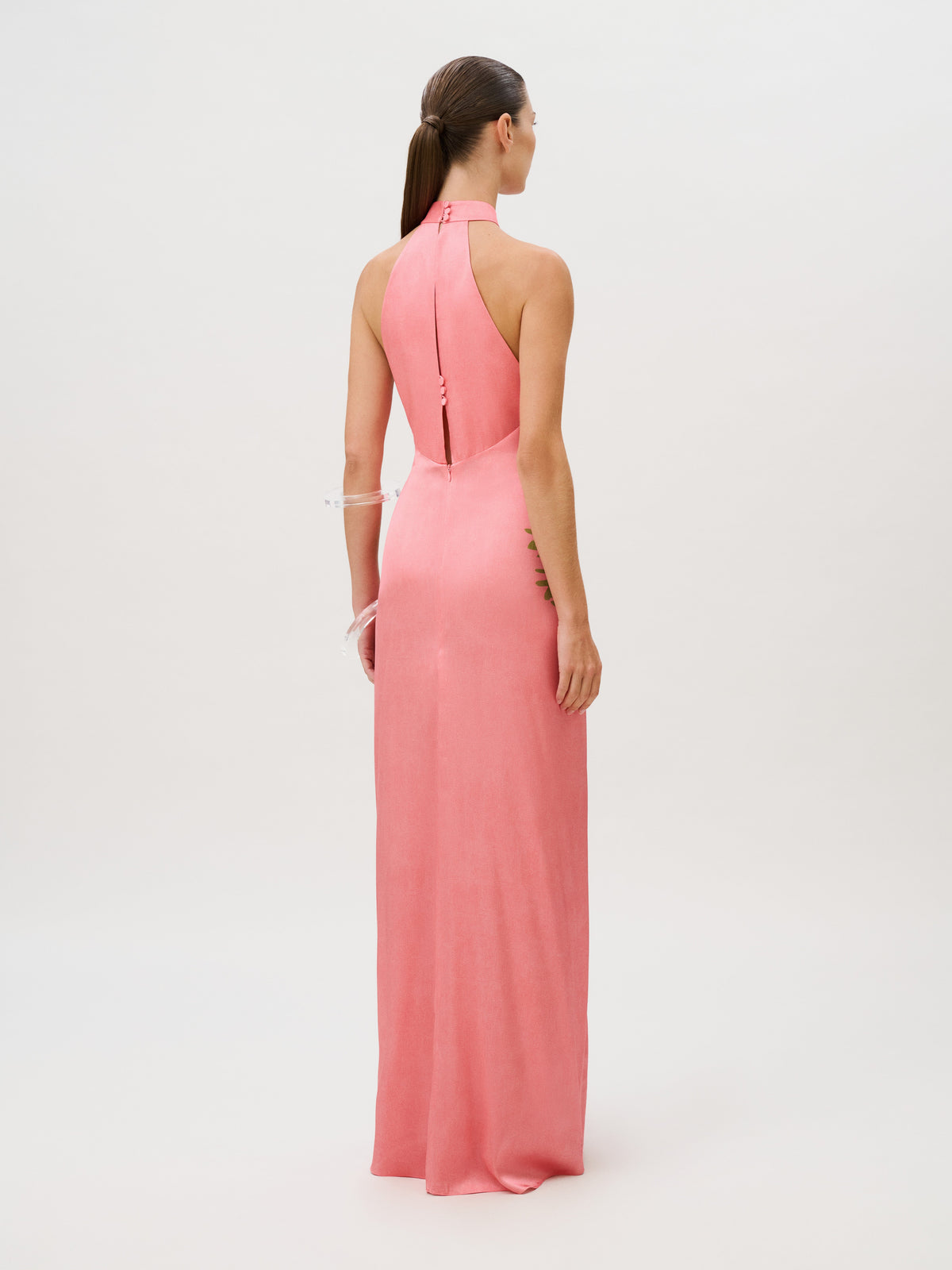 Back view of the Koori Dress, a floor-length pink silk halter gown with a high neck and vertical button detail at the upper back.