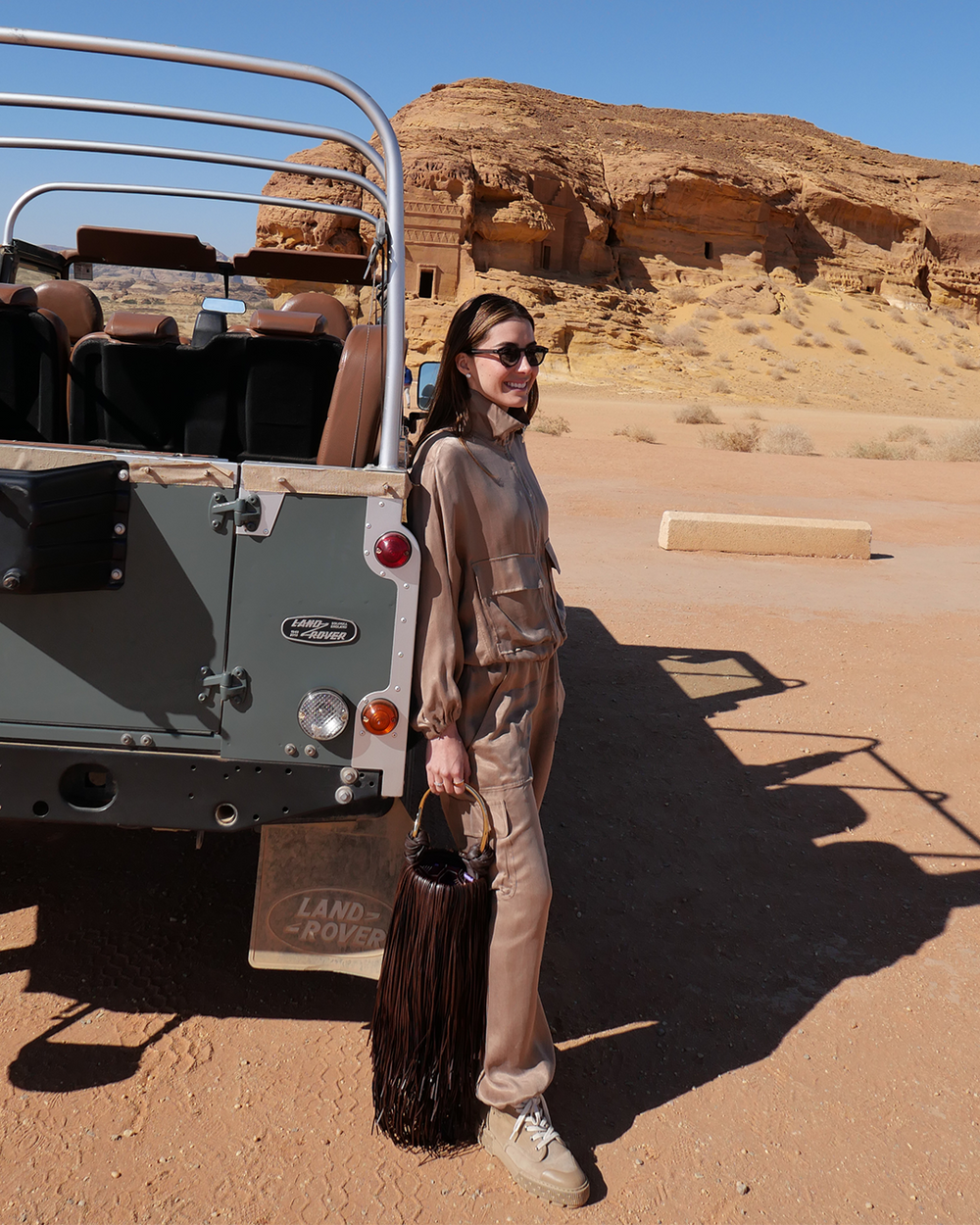 Person standing next to a Land Rover in a desert setting