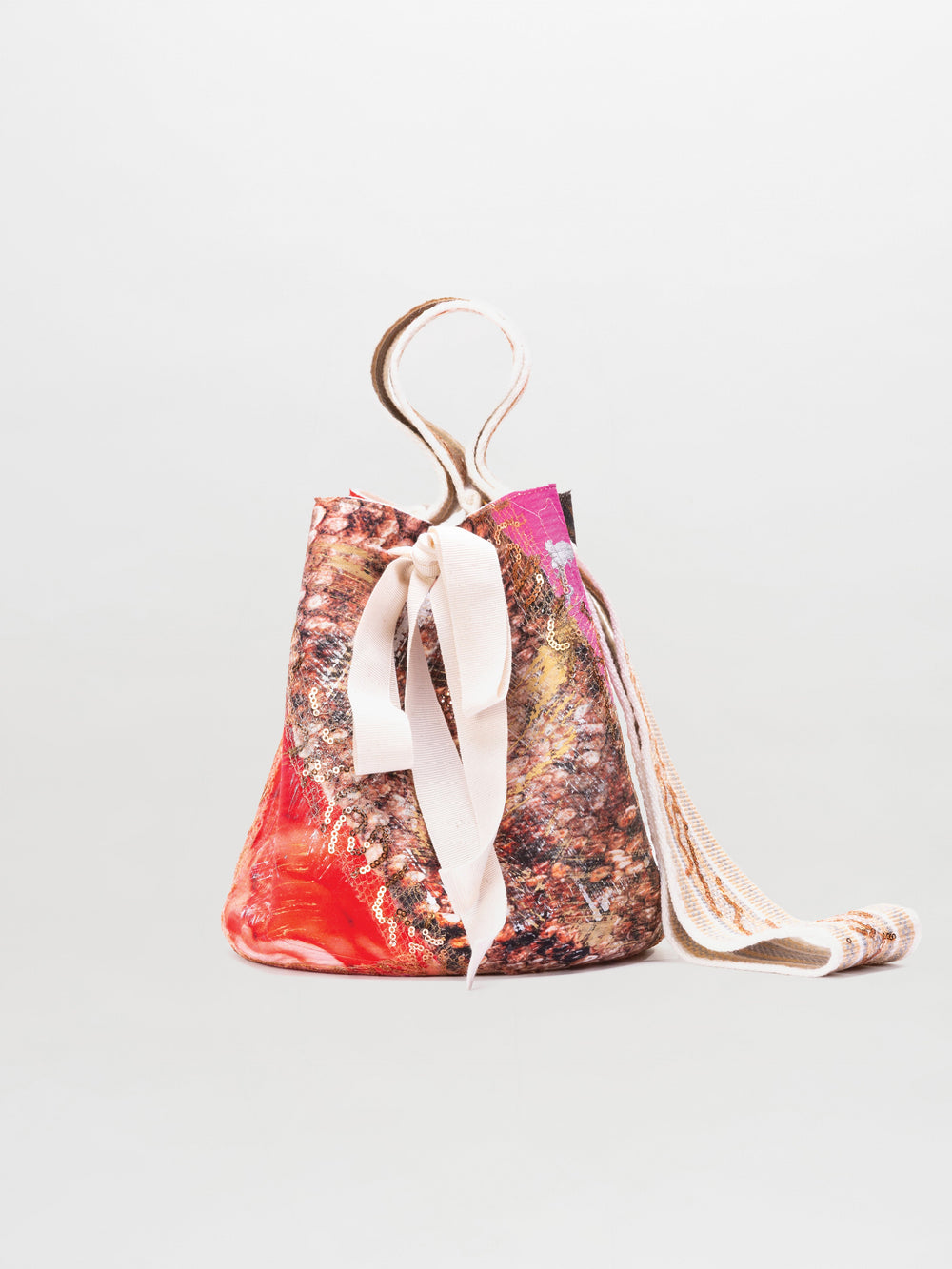 The Mochila Laaput Small is a colorful, textured Wayuu handbag featuring a marble-like pattern, white ribbon tie closure, and a long wide strap, displayed against a plain light background.