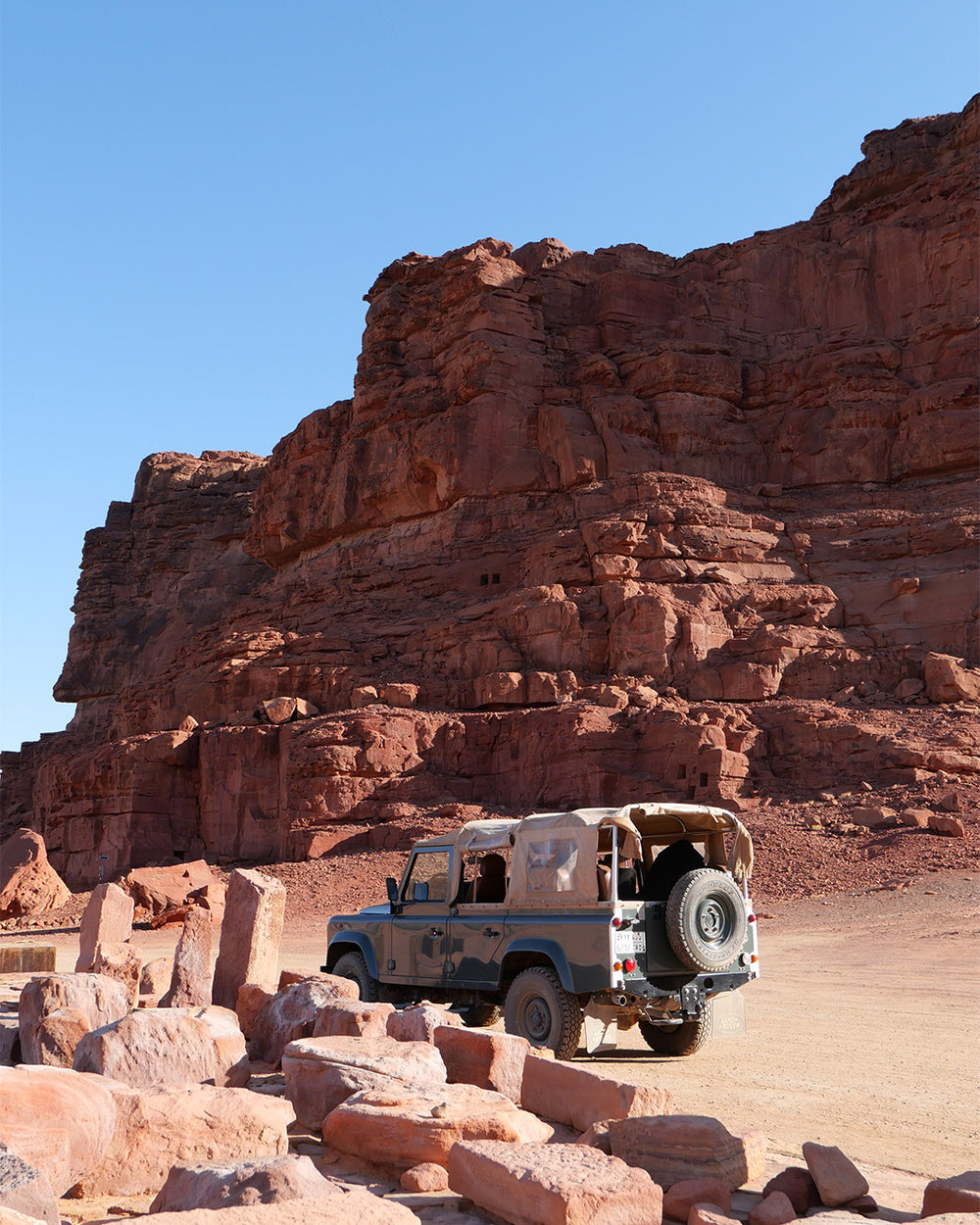 Jeep in a desert landscape with rocky formations and clear blue sky