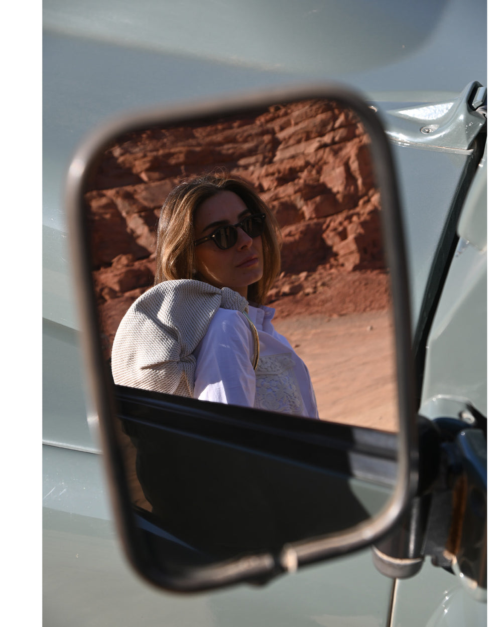 Woman reflected in a vehicle side mirror with desert landscape in the background