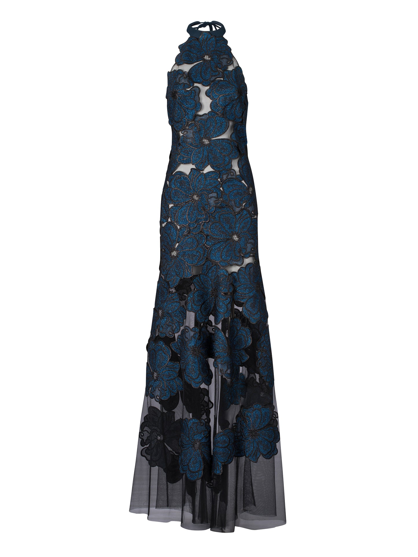 A woman is elegantly adorned in the Mab Dress Navy, featuring a halter-neck style with large floral blue appliques and sheer fabric, standing against a plain blue background, capturing the sophisticated essence of an August 19th gala.