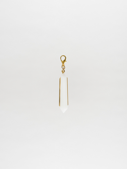 The Mariela Charm Pearl, a gold-tone and white crystal pendant crafted in a pointed shape, elegantly hangs against a plain white background, showcasing the signature Tcherassi design.