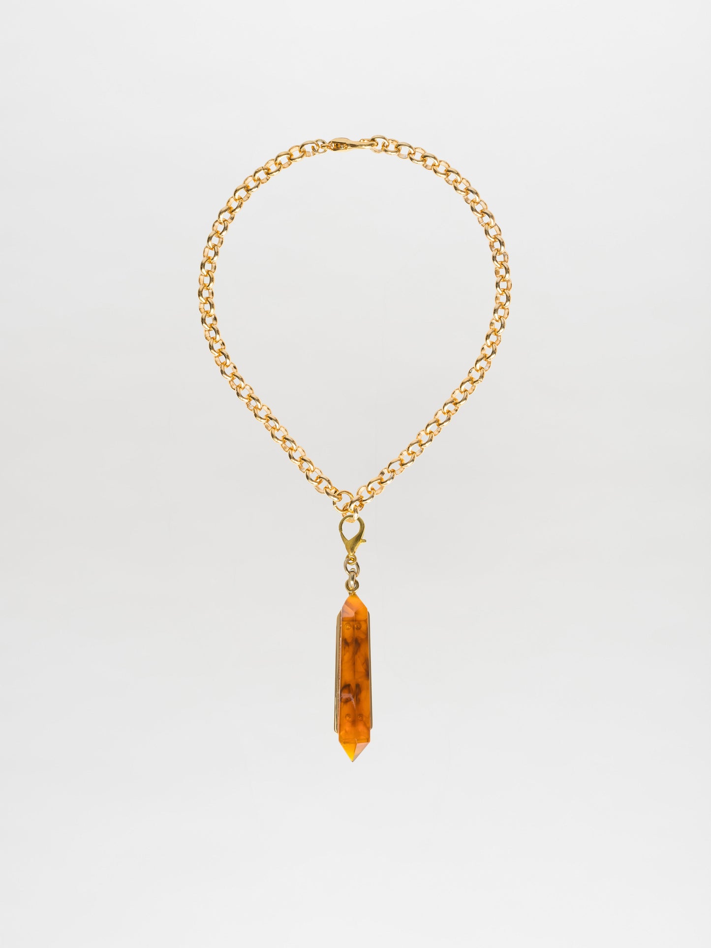 The Mariela Necklace Amber features a chic choker style, with a gold-plated brass chain adorned by a geometric crystal pendant in an amber hue.