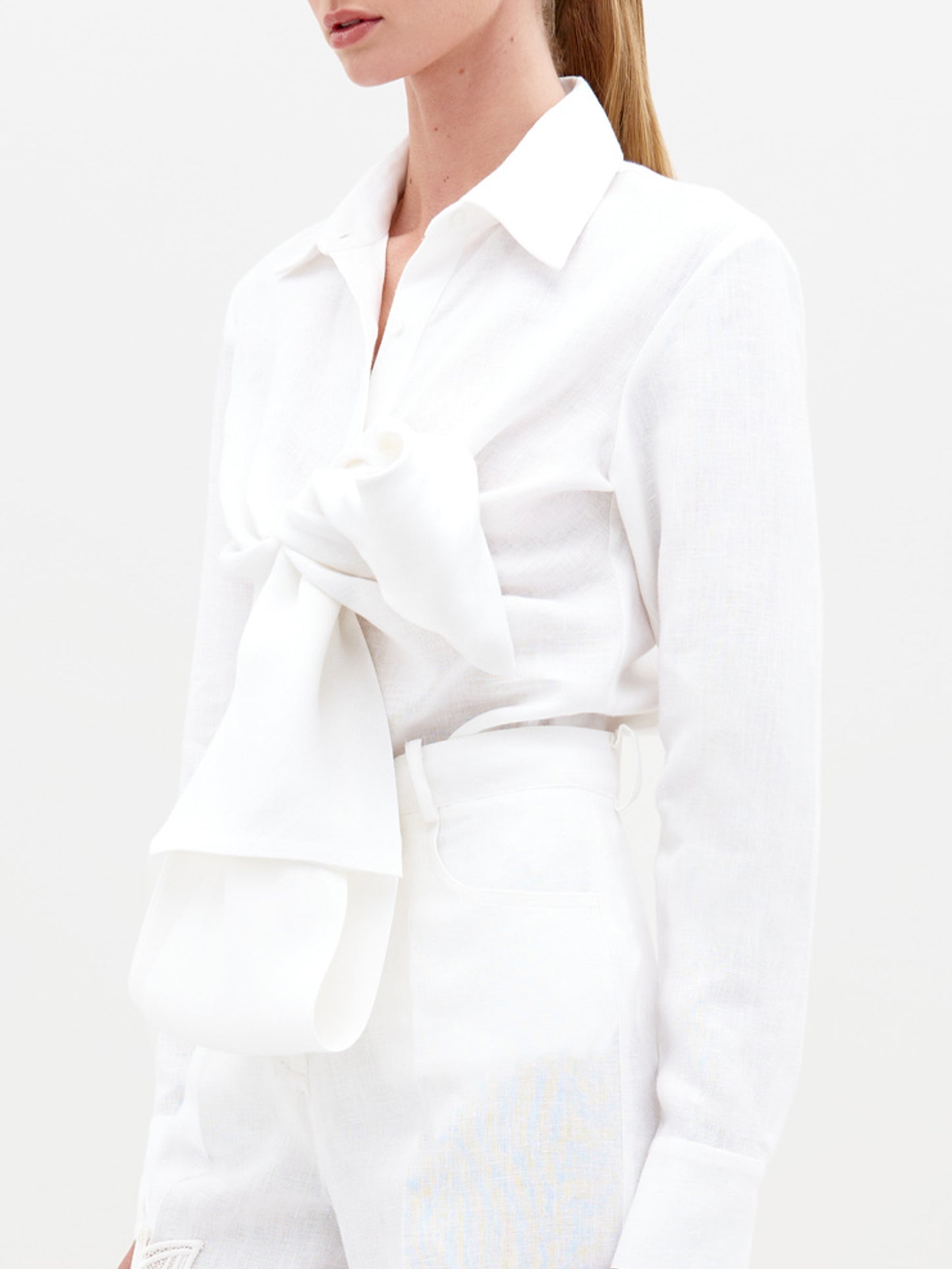 A blonde woman stands against a plain background wearing the Mercury Blouse