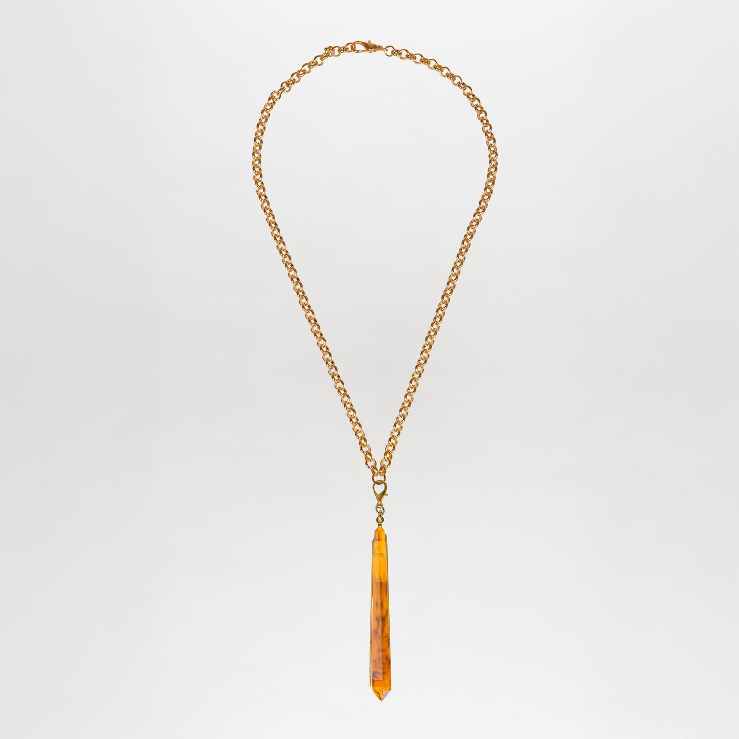 The Montse Necklace, a Tcherassi design, showcases a thin gold chain with a vertically hanging, long pointed amber pendant set against a plain white background.