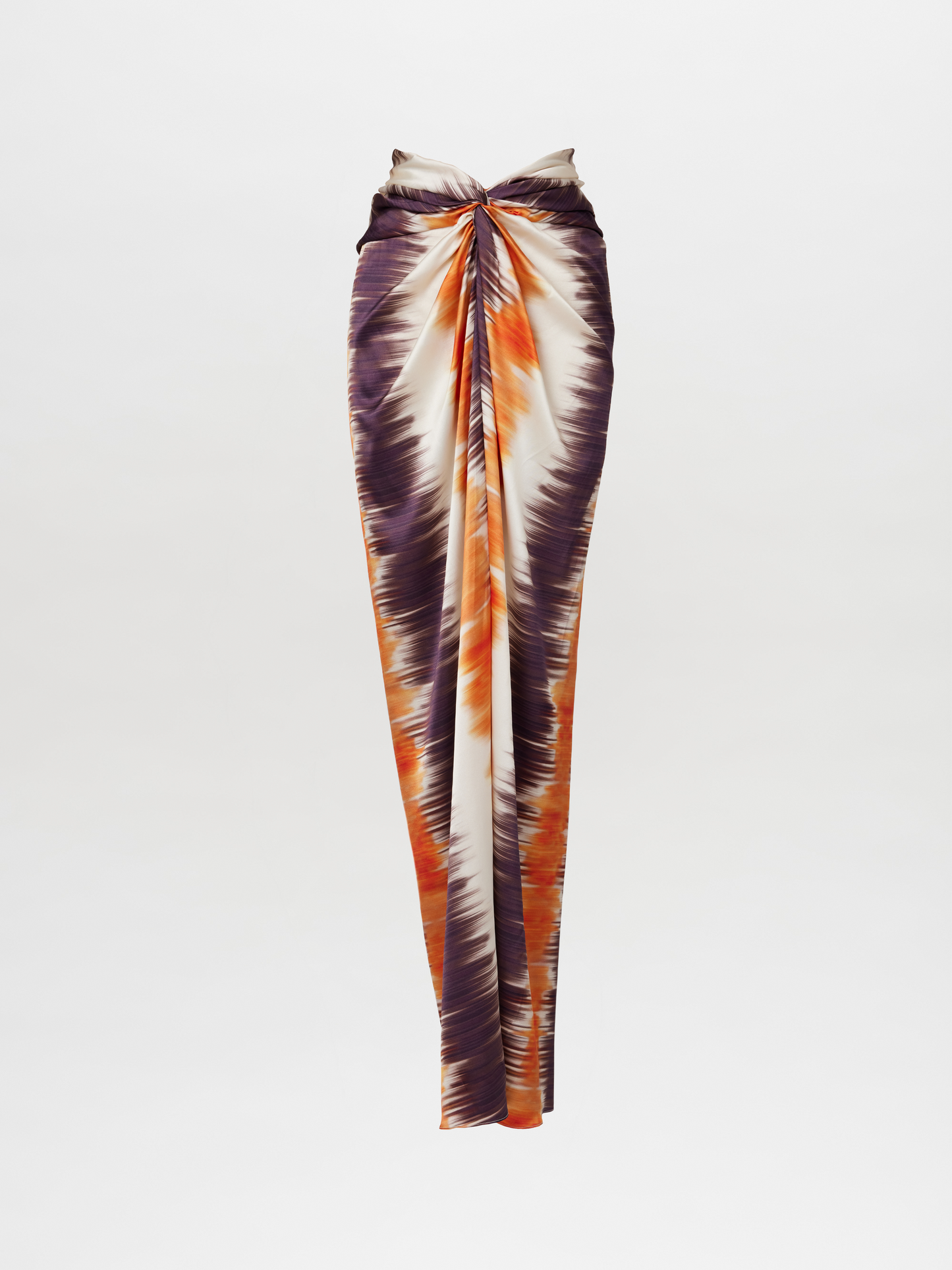 The Marina Skirt Mulberry Orange Hazy is an asymmetrical, long high-waisted maxi skirt showcasing a tie-dye pattern in purple, orange, and white hues, with a ruched central seam.