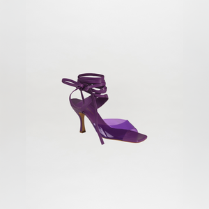 The Marlene Heels are purple high-heeled sandals made from luxurious Italian calf leather, featuring tie-around ankle straps, shown against a plain white background.